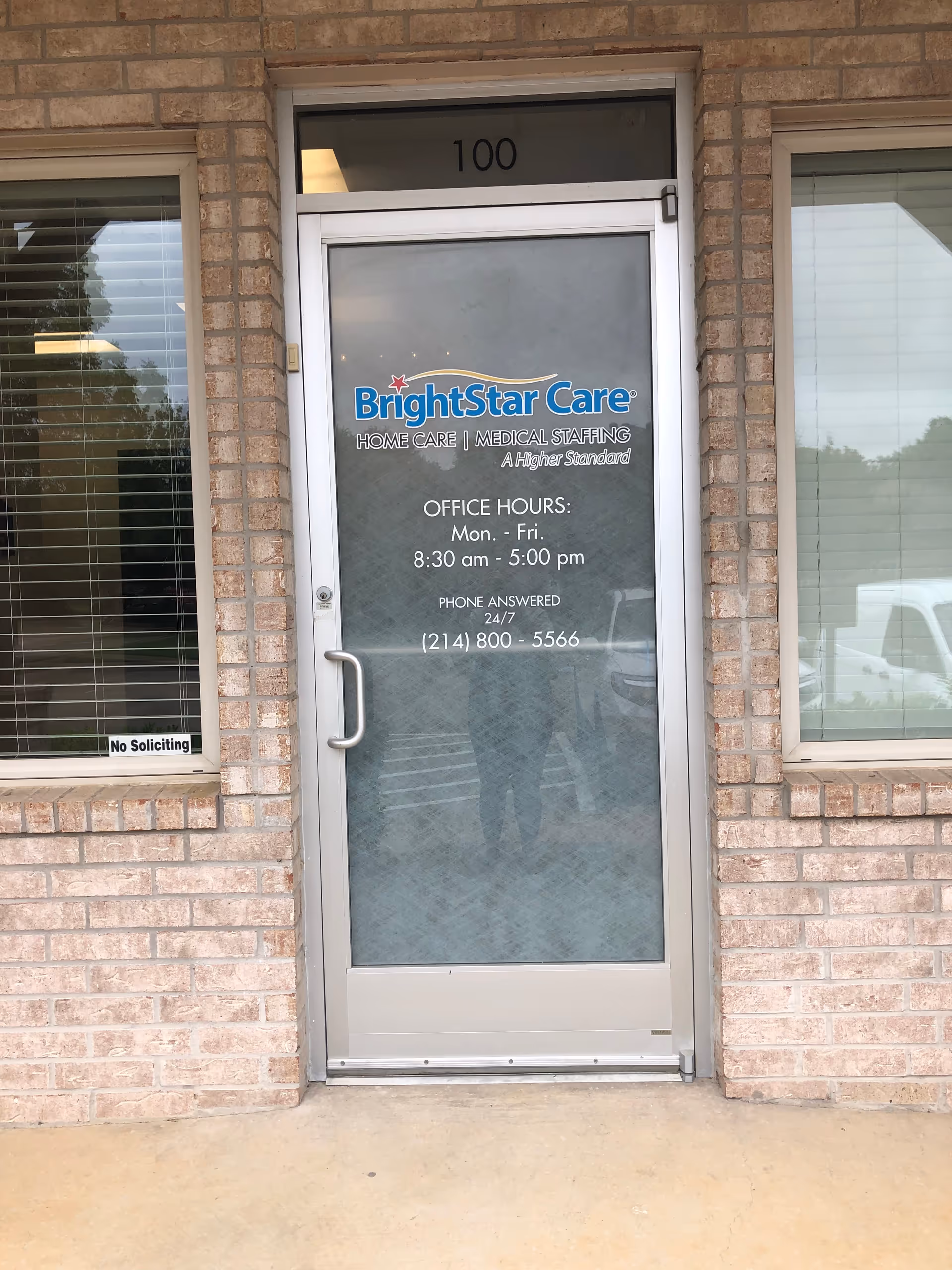 Front entrance door displaying BrightStar Care signage and office hours on brick building.