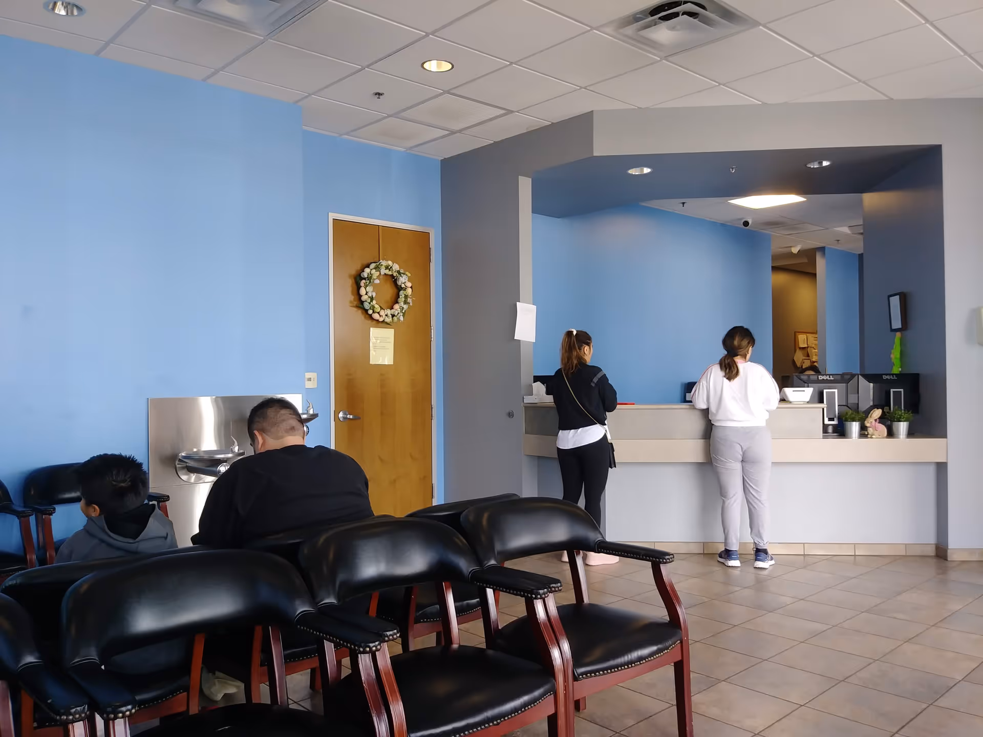Blue-walled lobby with a reception desk and two people at the counter.