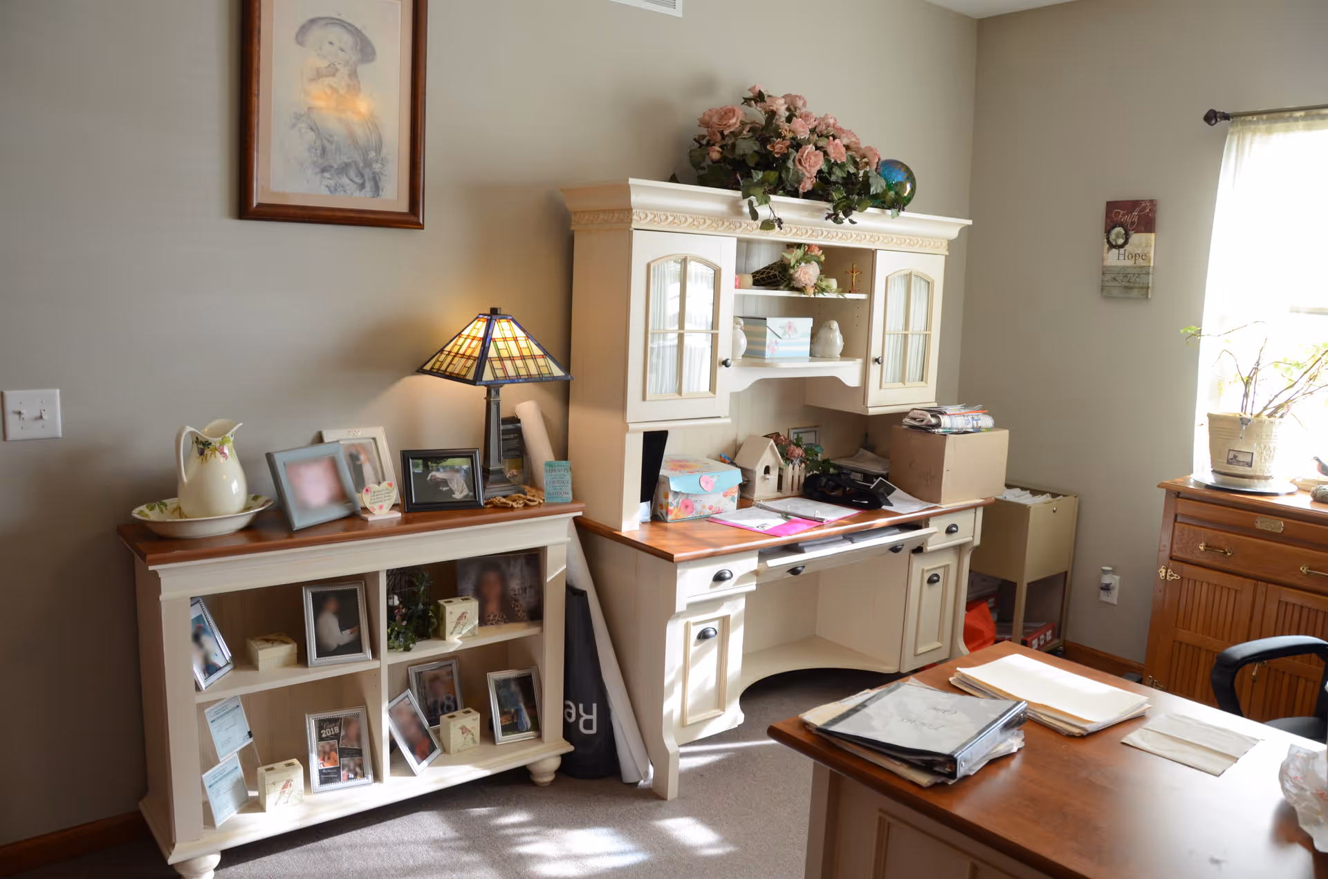 Cozy home office corner with white desk, hutch, photos, and decor