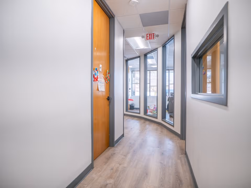 Narrow interior hallway in a senior living facility with curved windows and closed doors