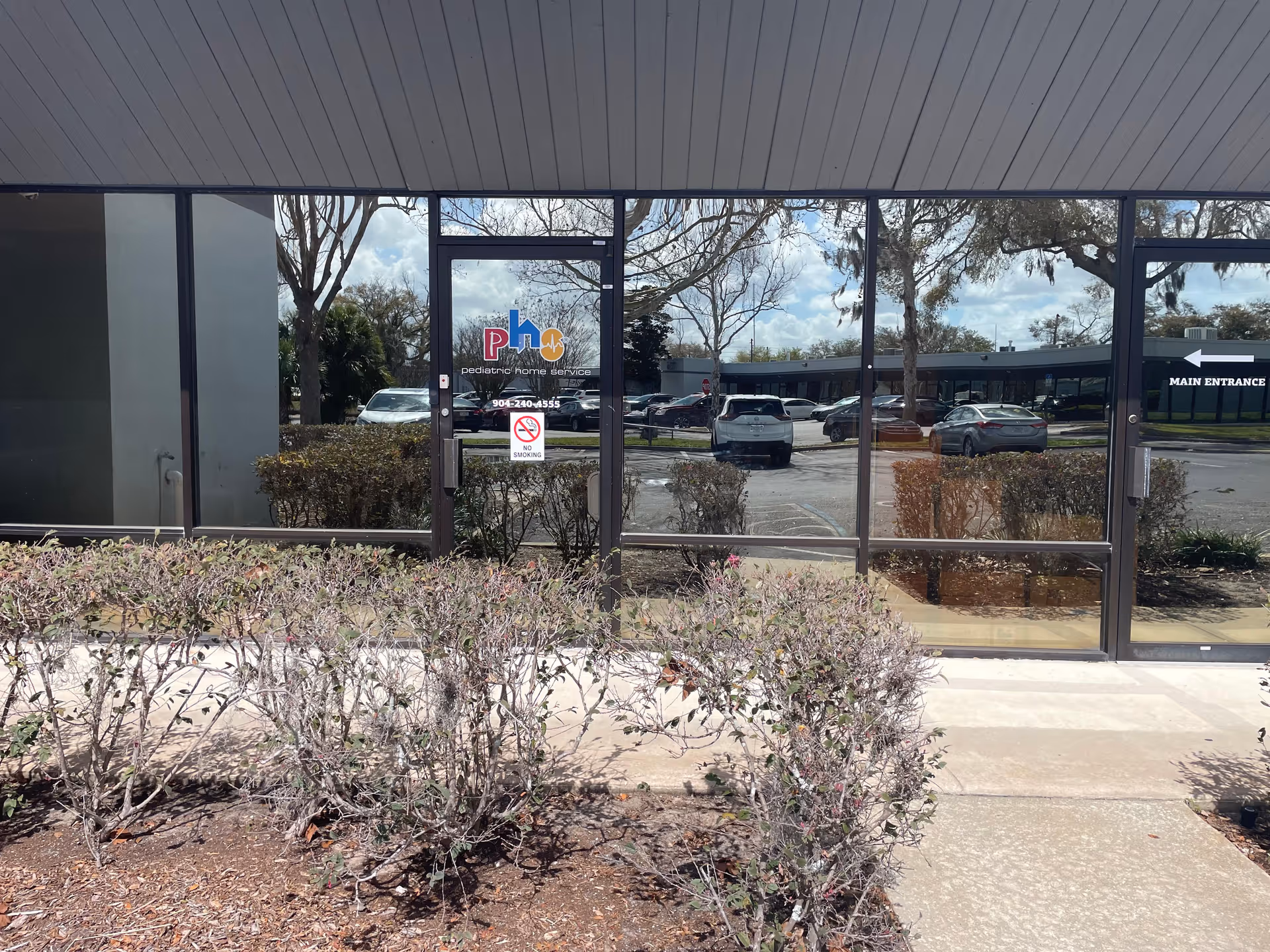 Glass entrance doors for Pediatric Home Service with a parking lot reflected in windows.