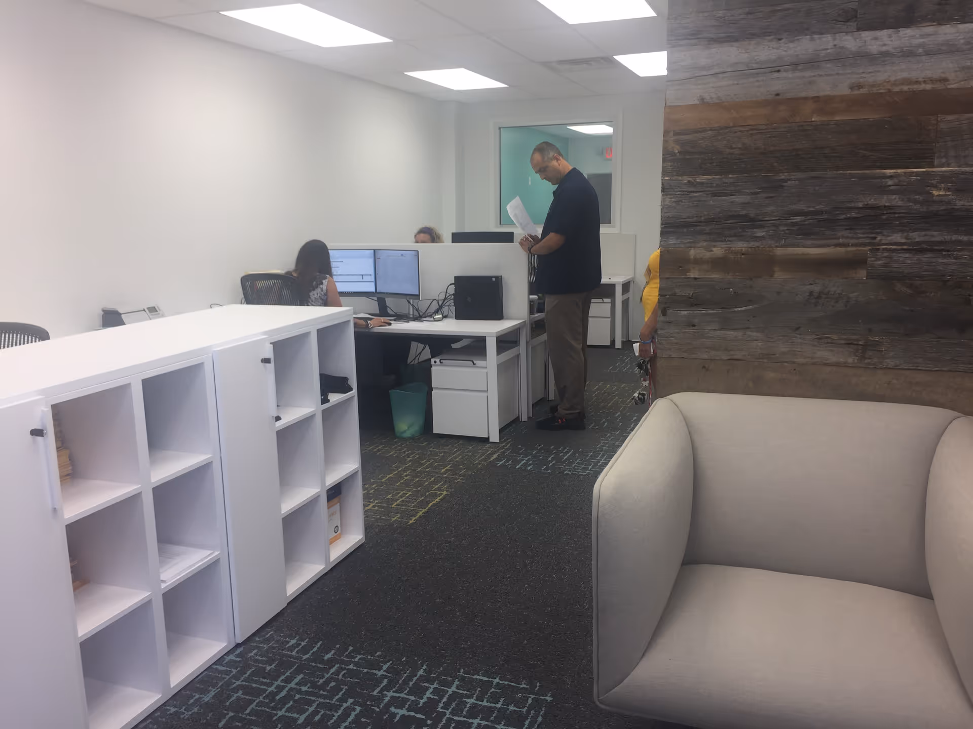 Office area in a senior facility with desks, computers, and a beige couch.