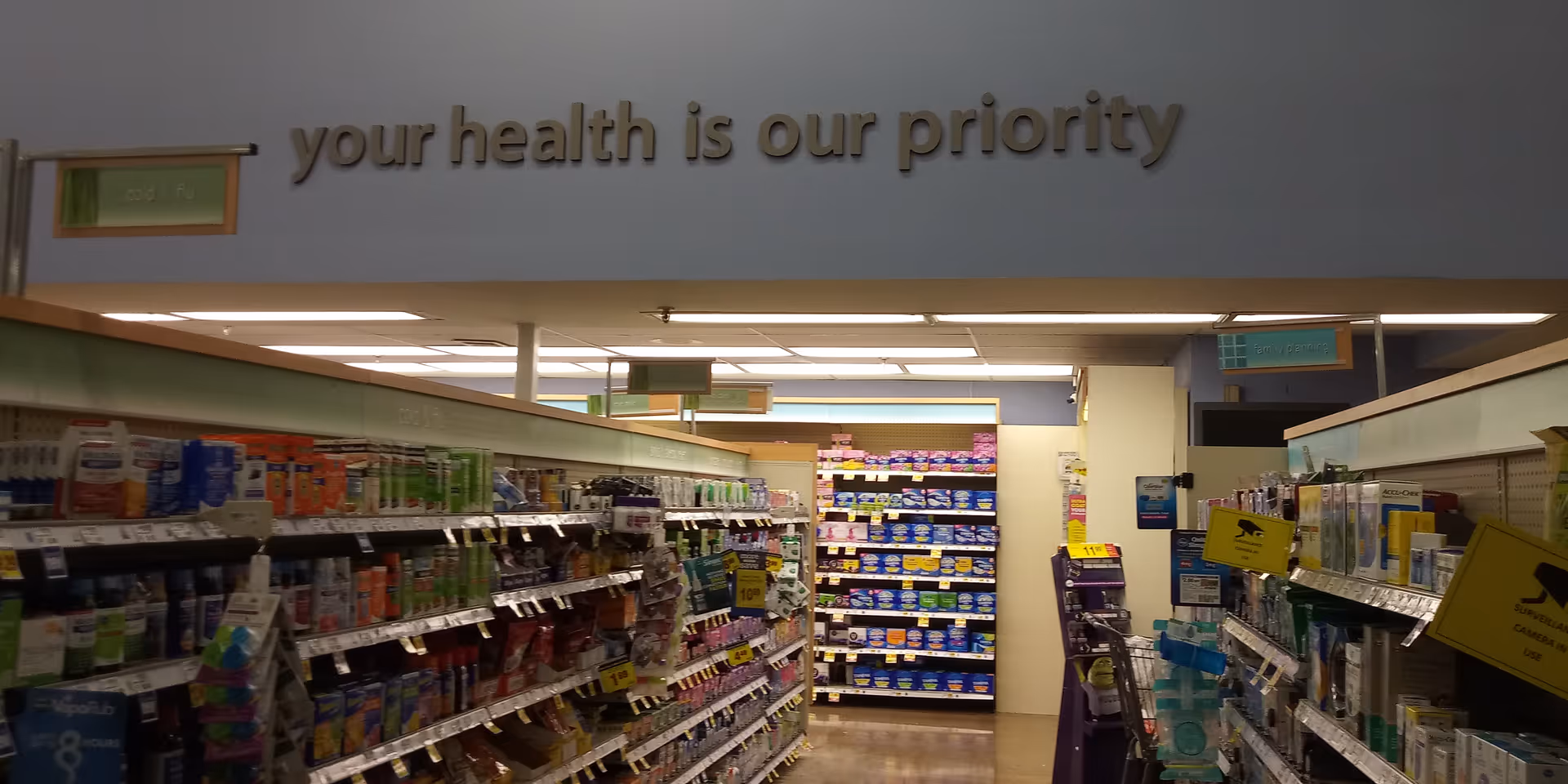 Interior of Kroger Pharmacy with aisles of products and your health is our priority sign.