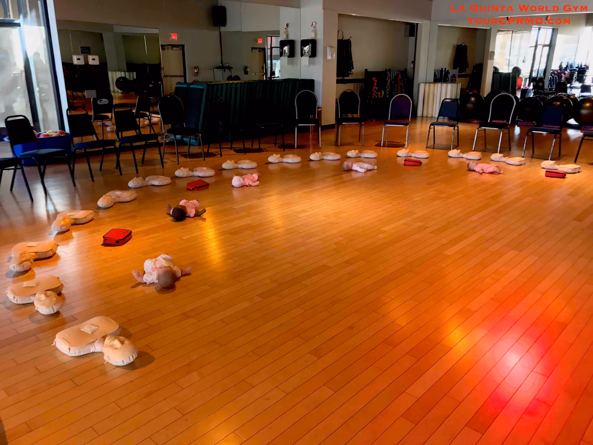 Indoor CPR training area with circular mannequin stations and surrounding chairs inside a gym style studio.