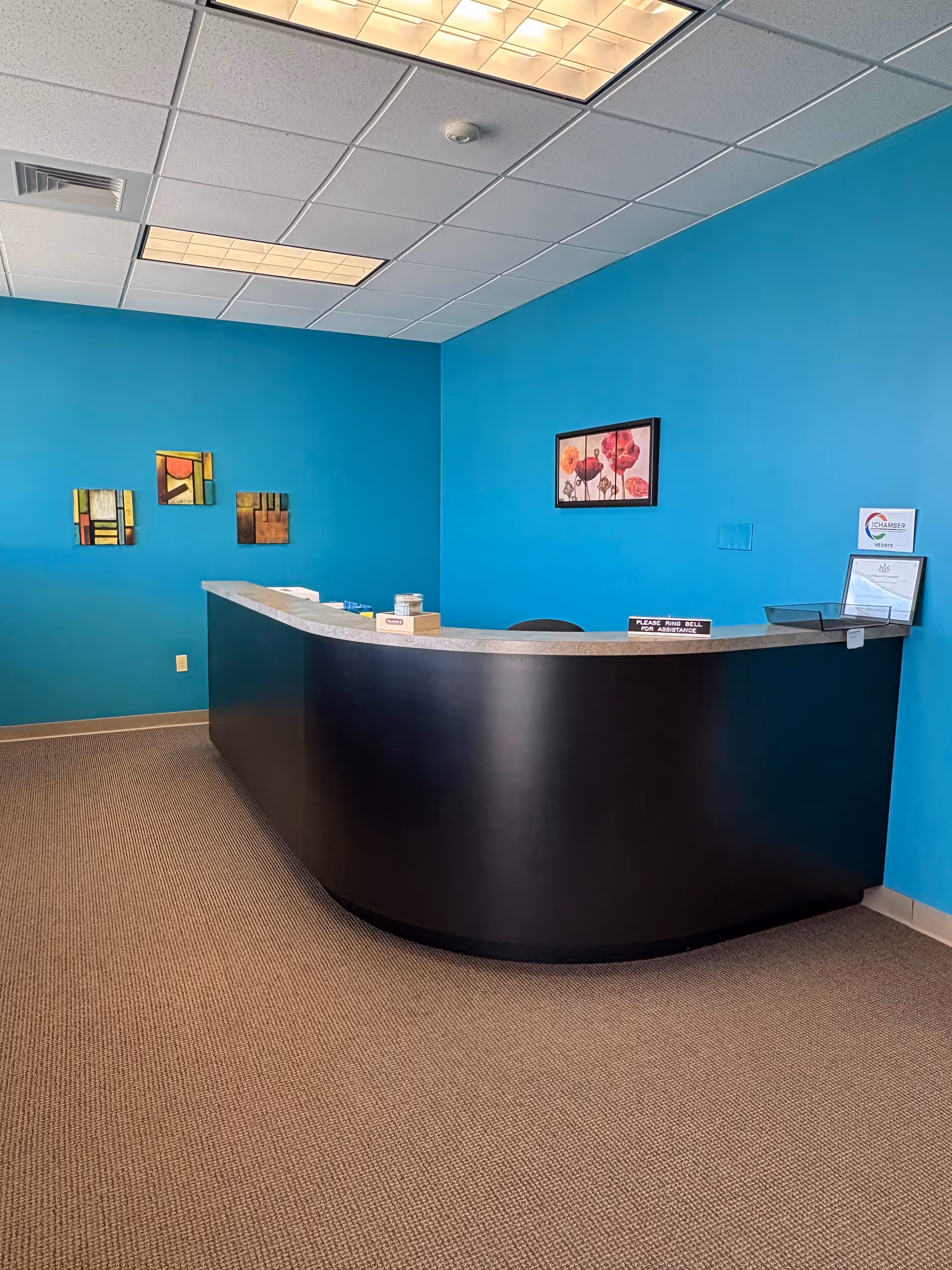 Blue-walled reception area with a curved black-and-white front desk in a senior living facility.