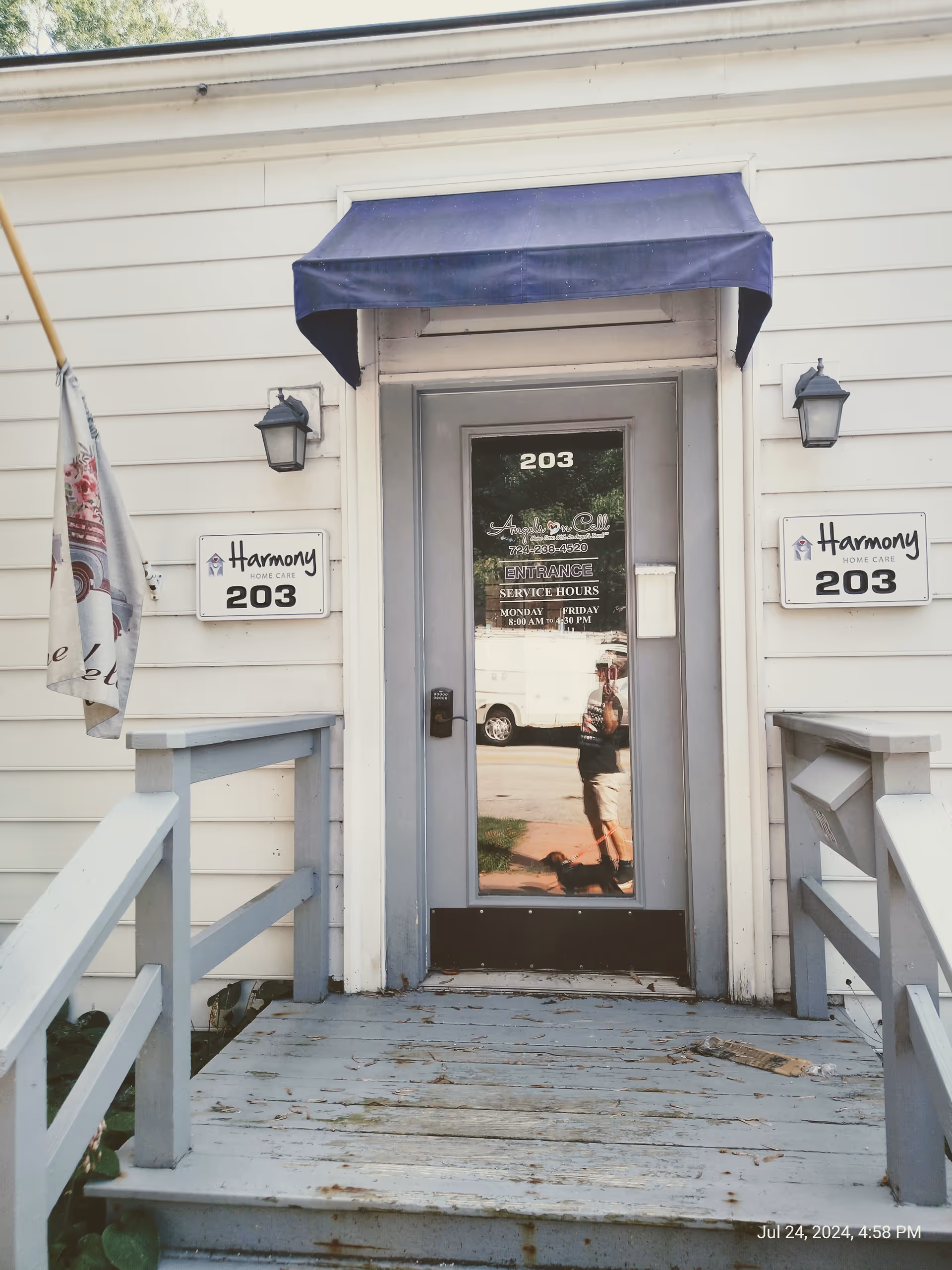 Front entrance of Harmony Home Care with a blue awning, white siding, and a ramped porch.