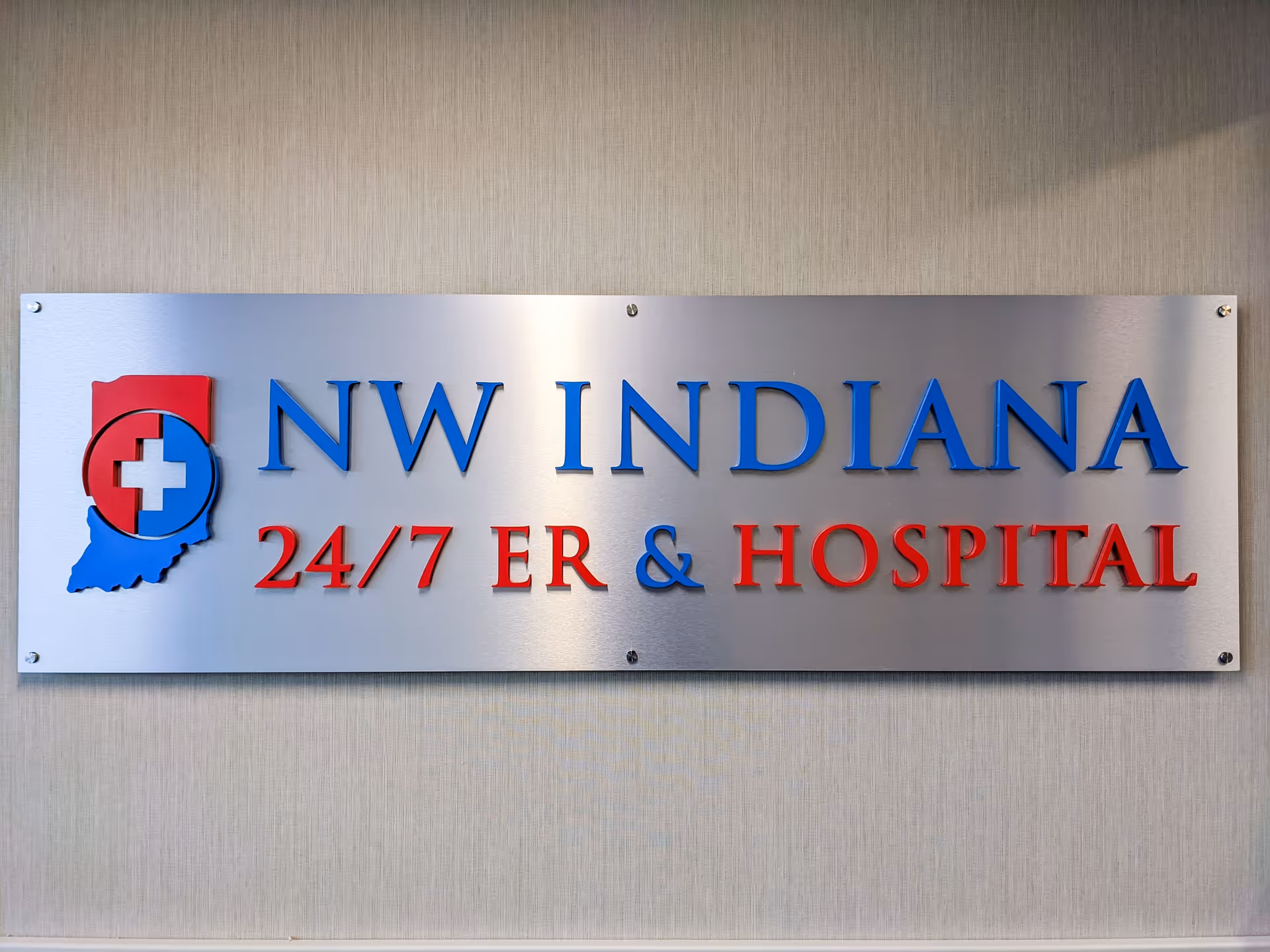 Metal plaque on wall reads NW INDIANA 24/7 ER & HOSPITAL with logo.