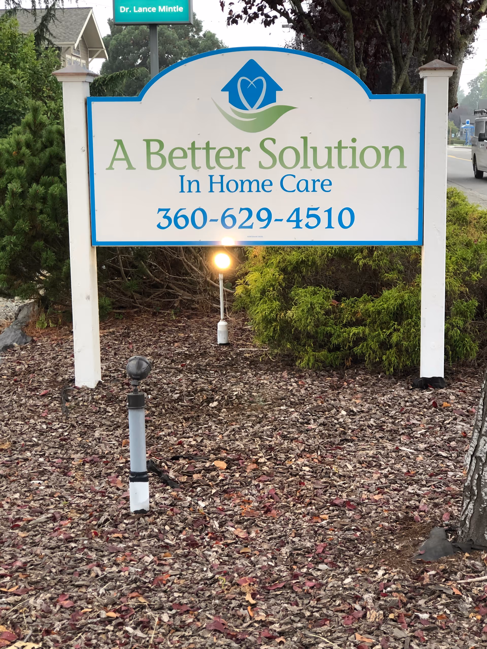 Outdoor sign for A Better Solution In Home Care near shrubs.