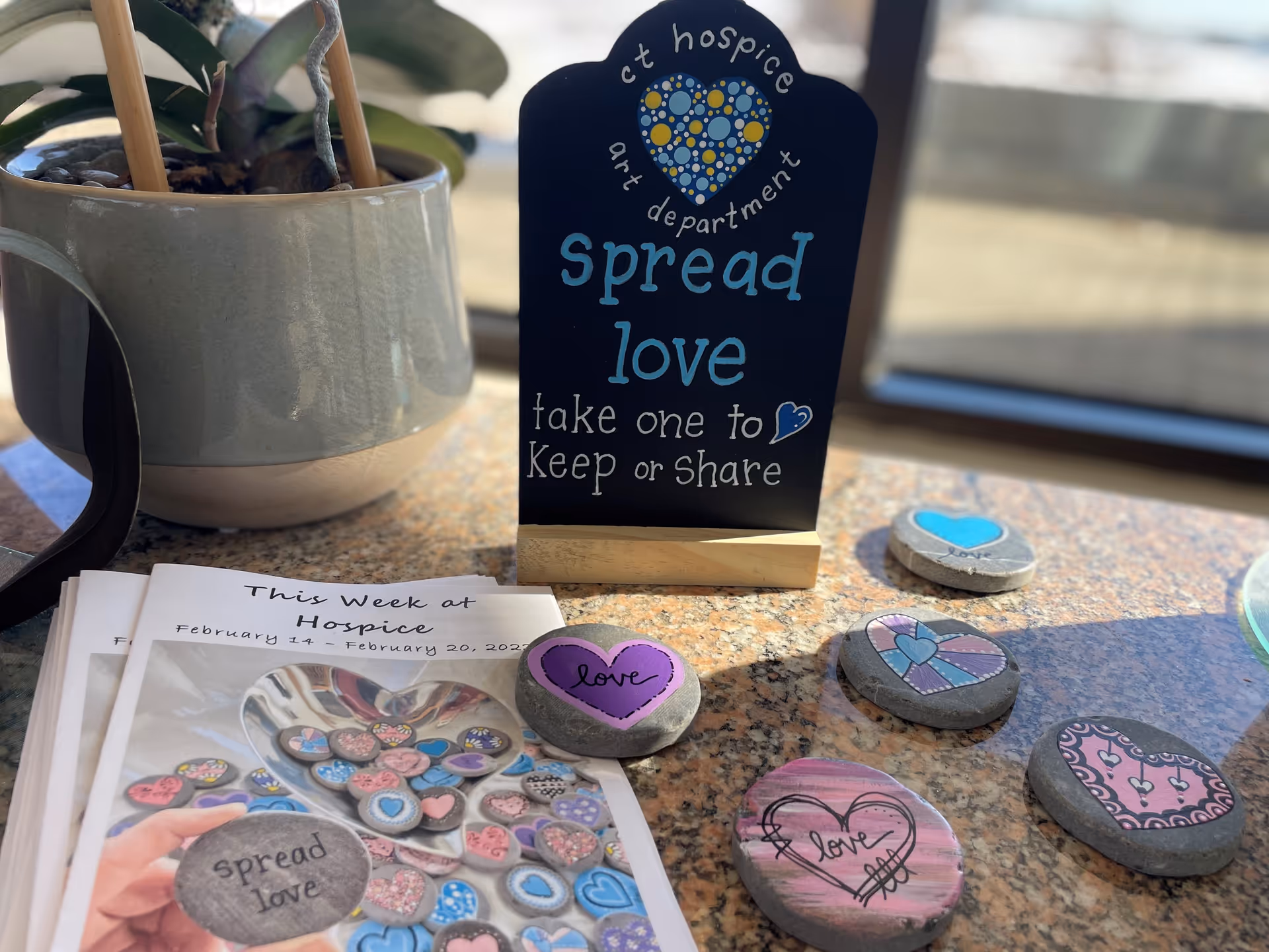 A tabletop display at Connecticut Hospice featuring heart rocks and a Spread love sign