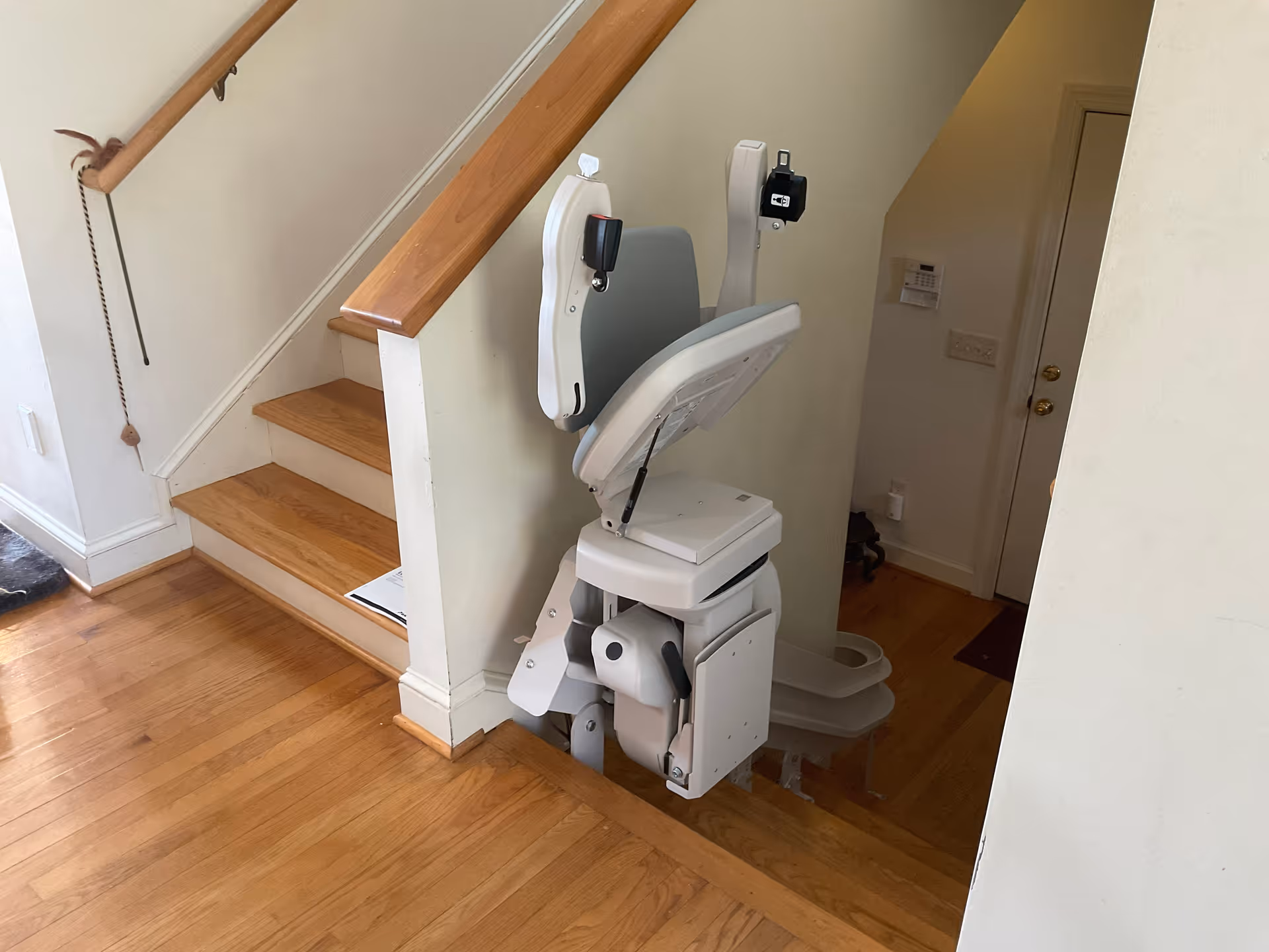 Indoor stair lift chair installed along a wooden staircase in a home interior.