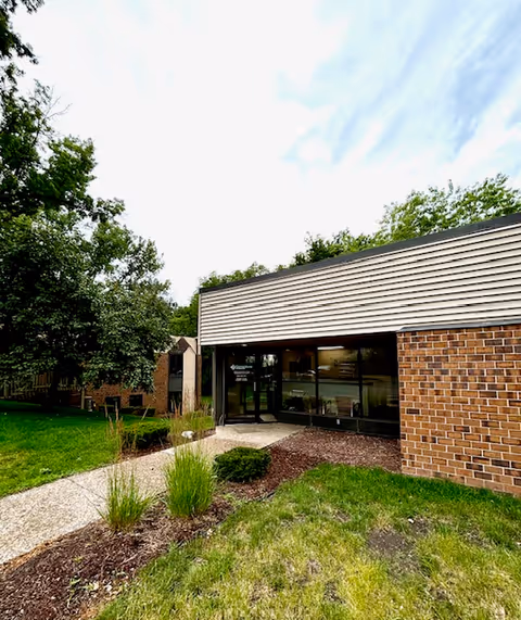 Front exterior of Cornerstone Caregiving building with brick walls, glass entrance, and landscaped path.
