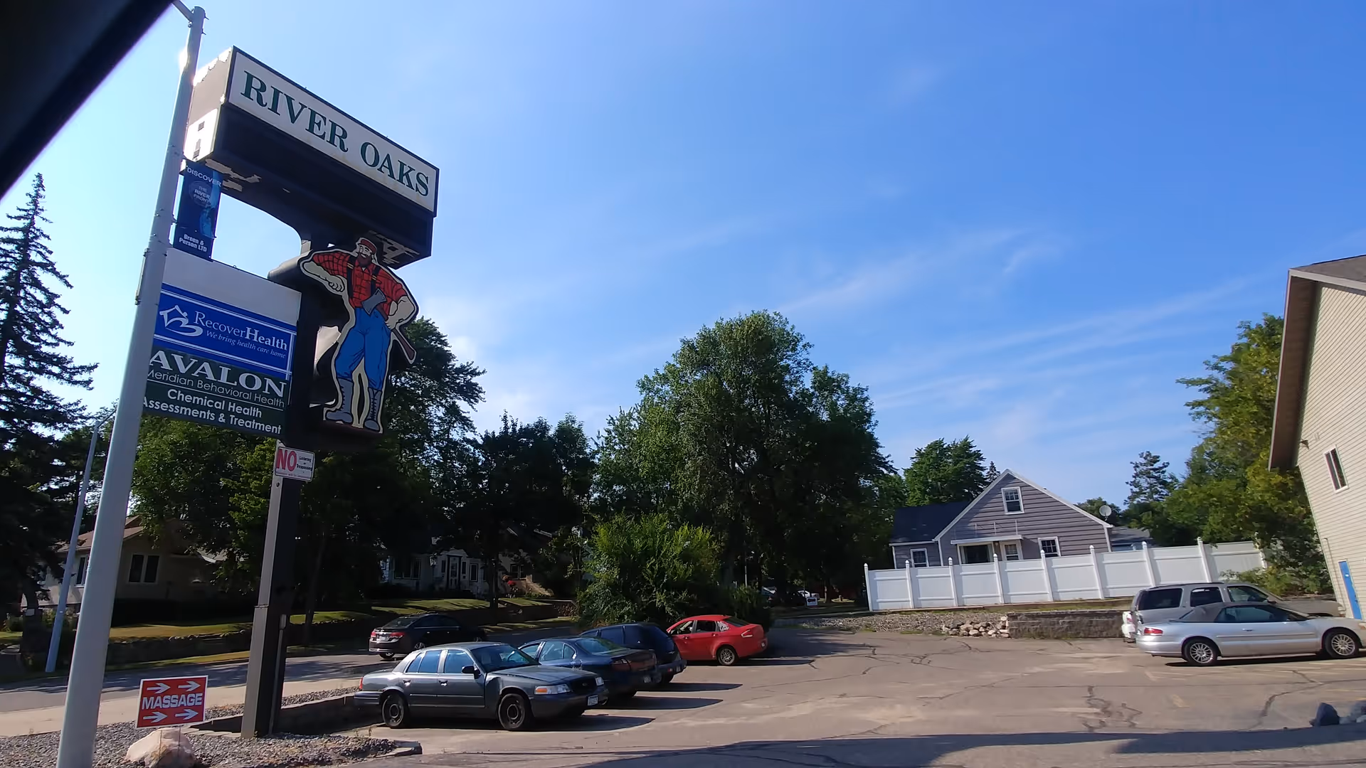 Exterior view of Aveanna Home Health sign at River Oaks with parked cars.