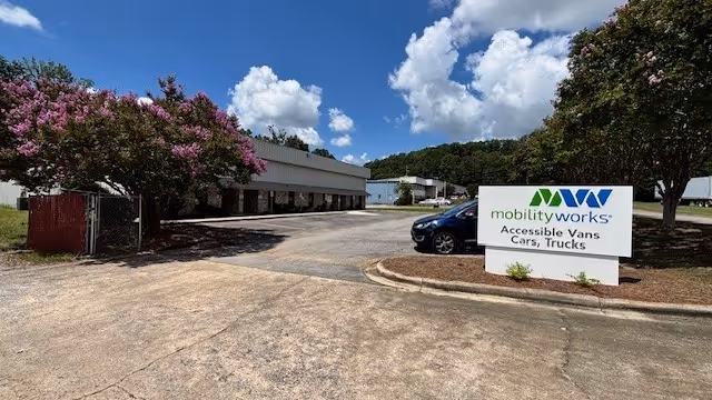 Exterior view of MobilityWorks facility with parking lot, sign, and trees