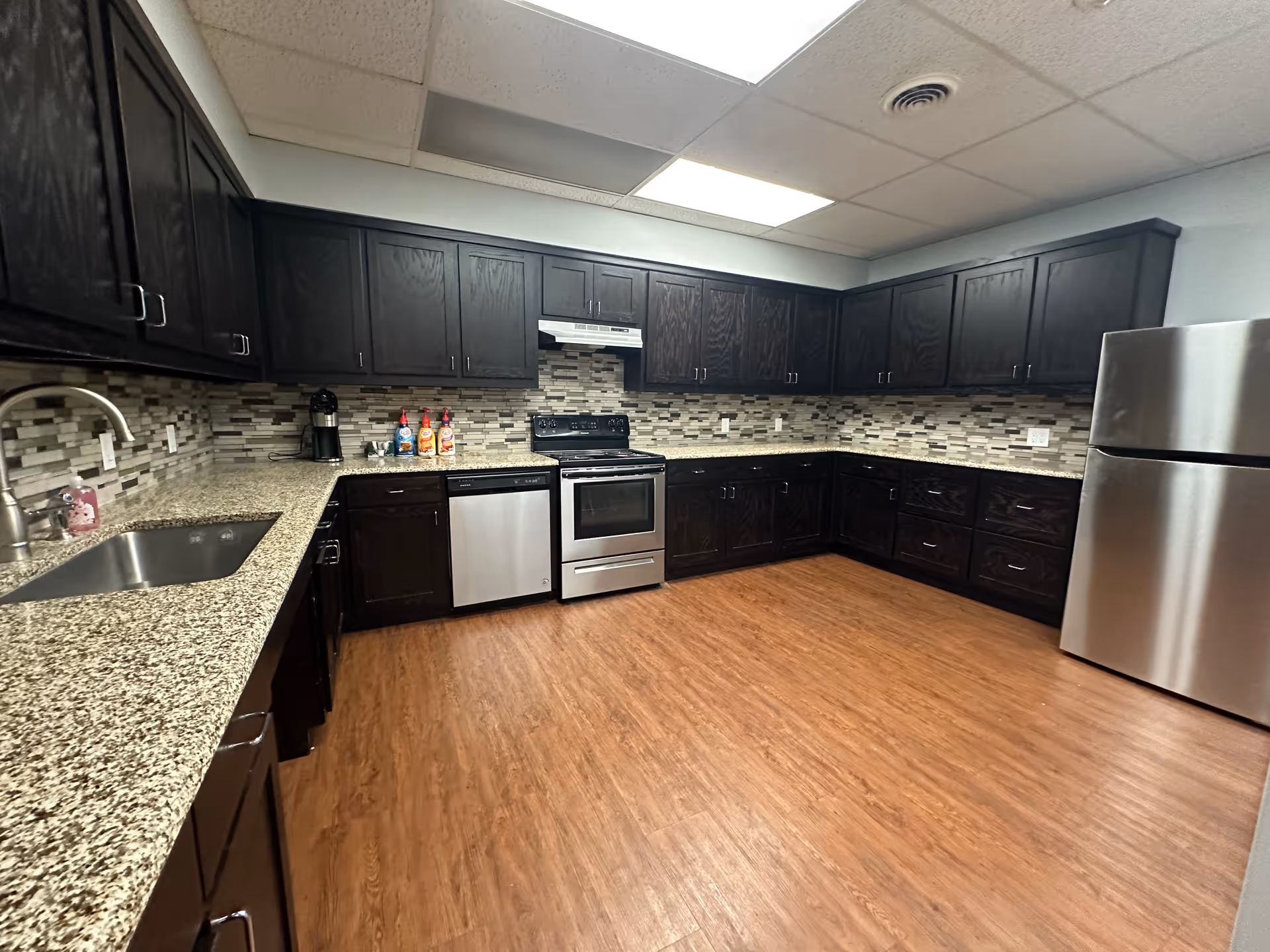 L-shaped kitchen with dark wood cabinets, stainless appliances, and granite countertops.