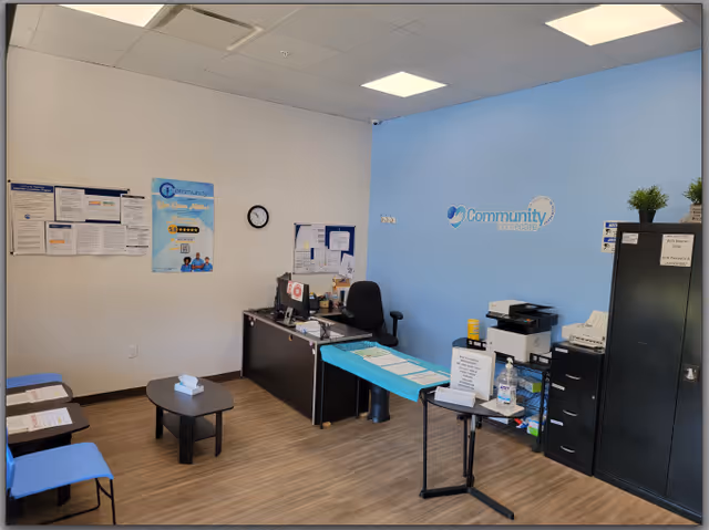 Office interior with blue wall, Community logo, desk, chair, and filing cabinet.