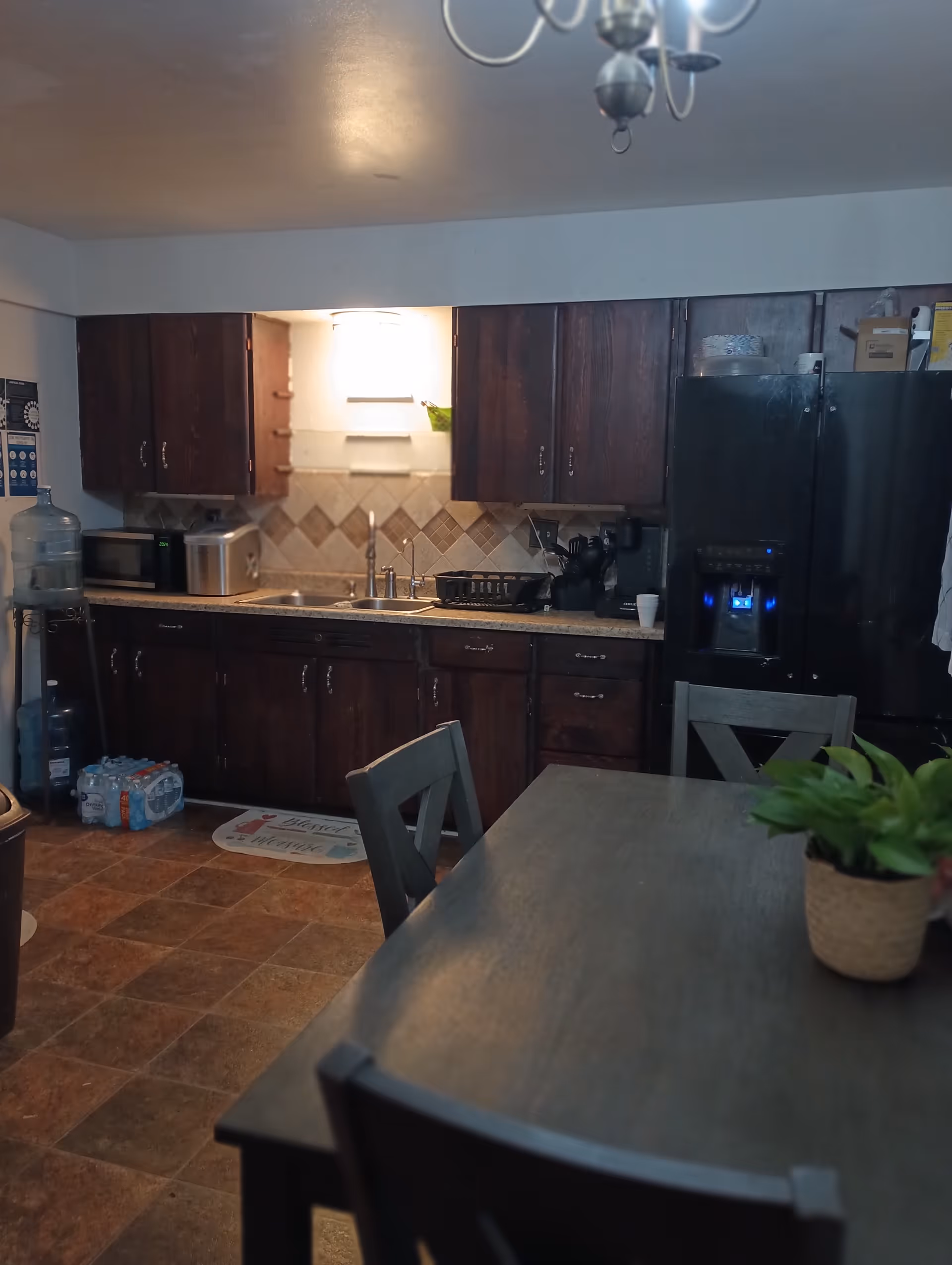 Dark wooden kitchen with dining table, cabinets, and stainless appliances.