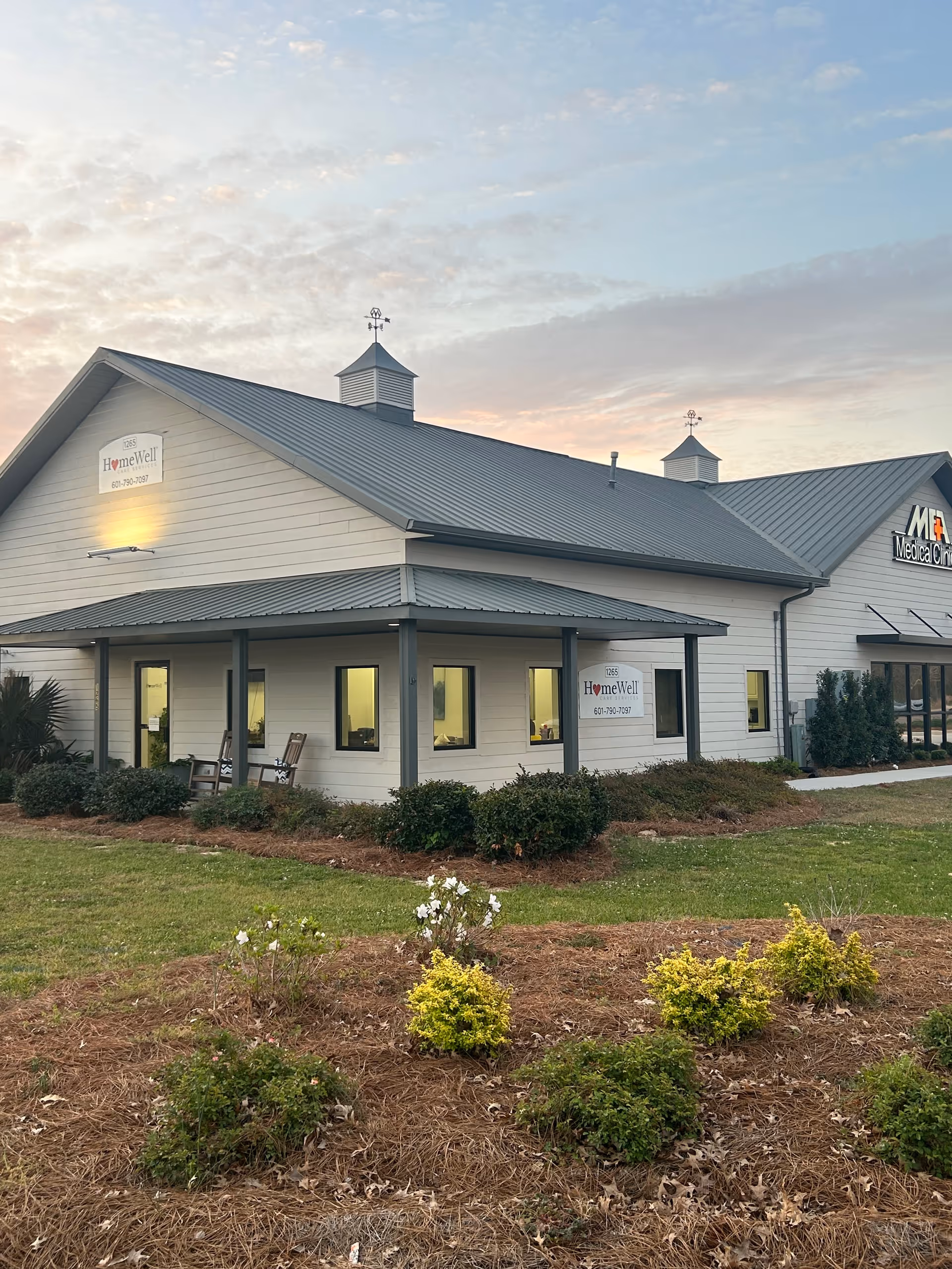 Exterior view of a HomeWell Care Services facility with a sign and landscaped front yard.