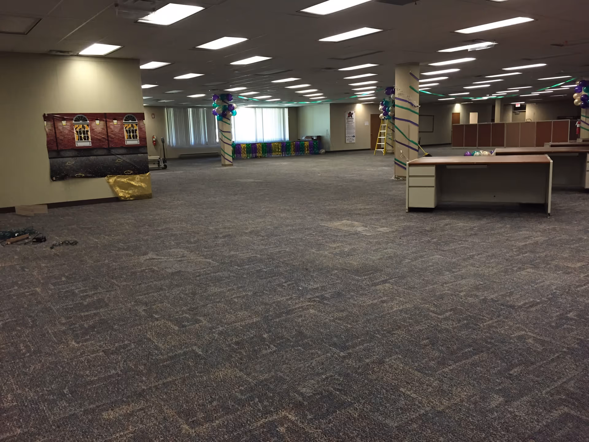 A large, empty interior hall in a senior facility decorated with balloons and streamers.
