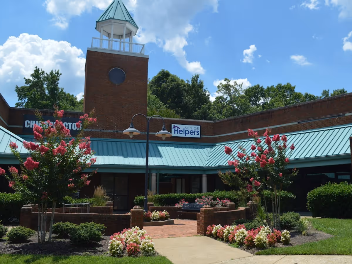 Exterior view of Senior Helpers facility with courtyard, flowers, and benches.