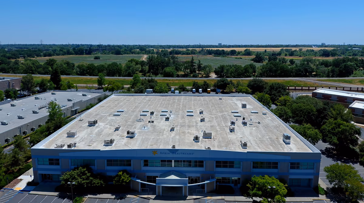 Aerial view of an Apria Healthcare facility with a flat roof and surrounding greenery.