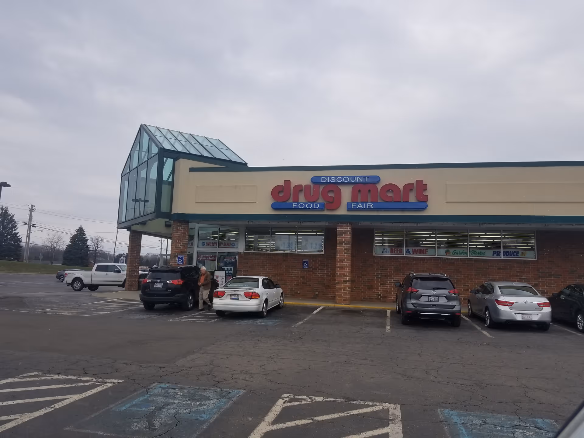Exterior view of a Discount Drug Mart storefront with parked cars in front.