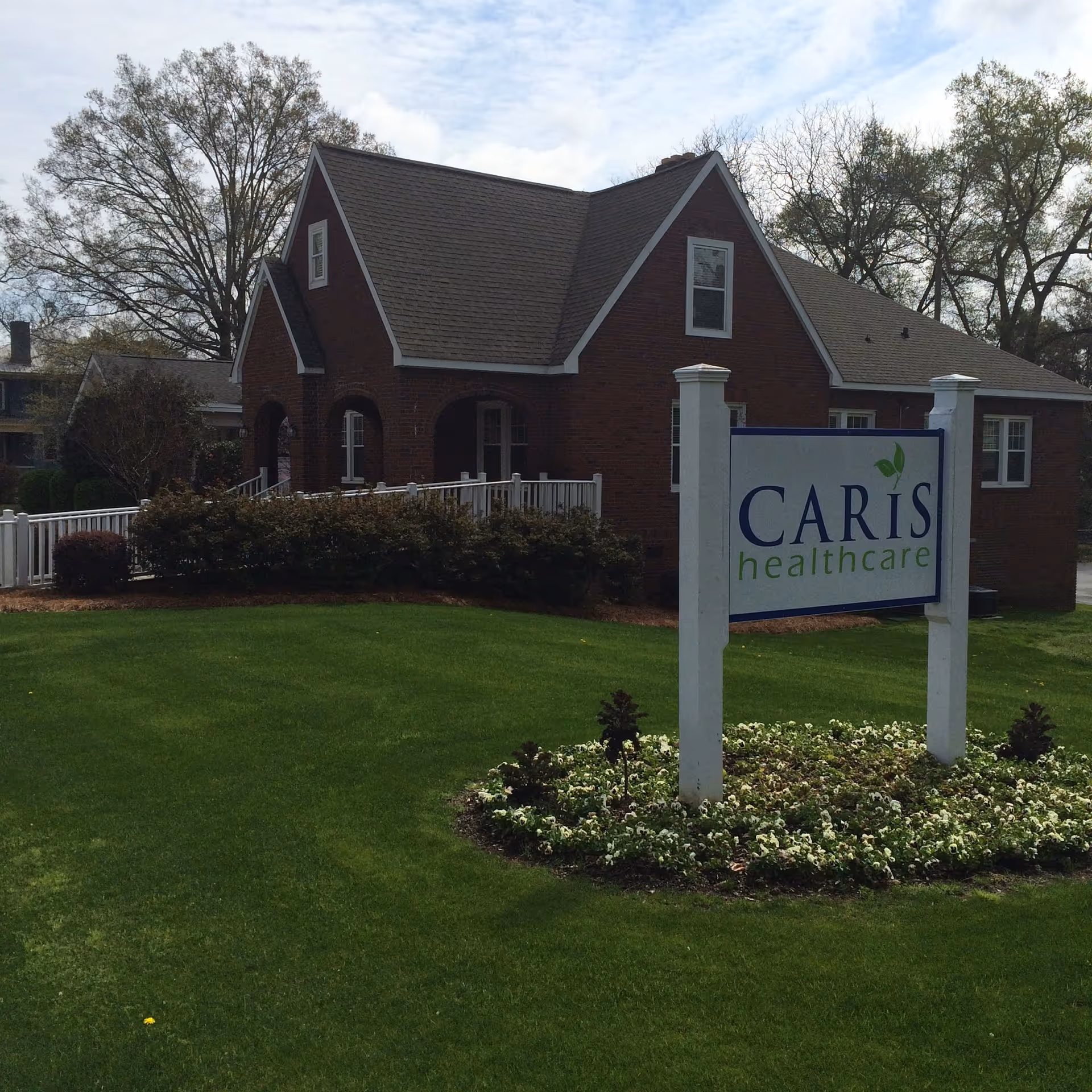 Brick senior care building with a CARIS healthcare sign on a manicured lawn.
