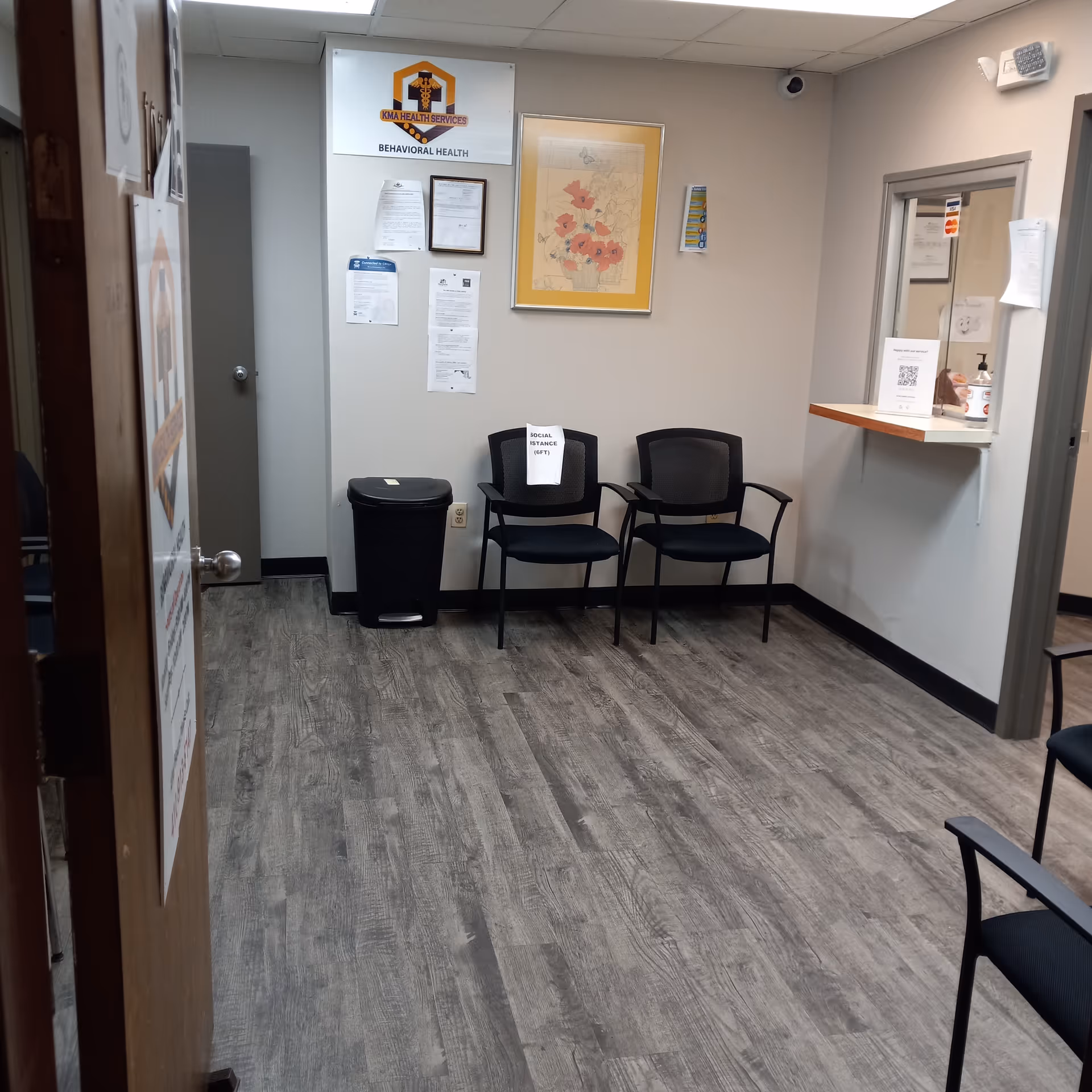 Interior waiting area with black chairs, a trash bin, and a framed map on the wall.