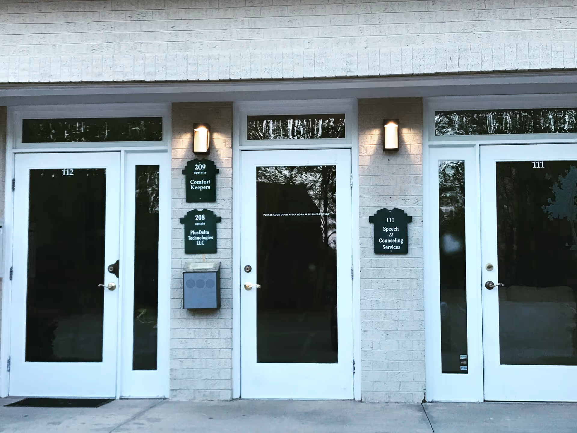 Front entrance of Comfort Keepers Home Care with glass doors and signs.