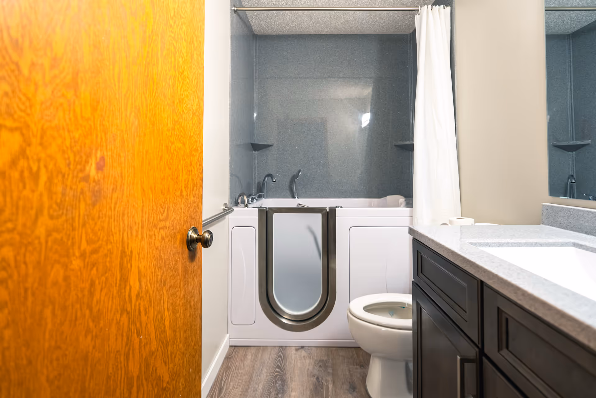 Open door reveals a bathroom with tub/shower, toilet, and dark vanity.