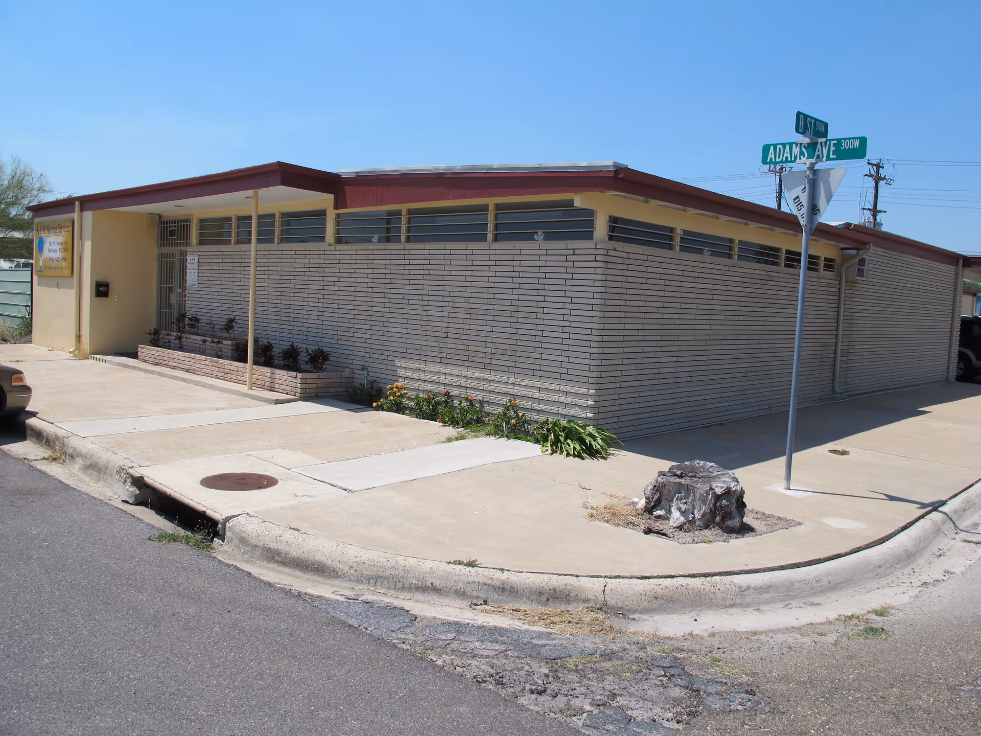 Single-story beige-brick facility at a street corner with a covered entrance and minimal landscaping.