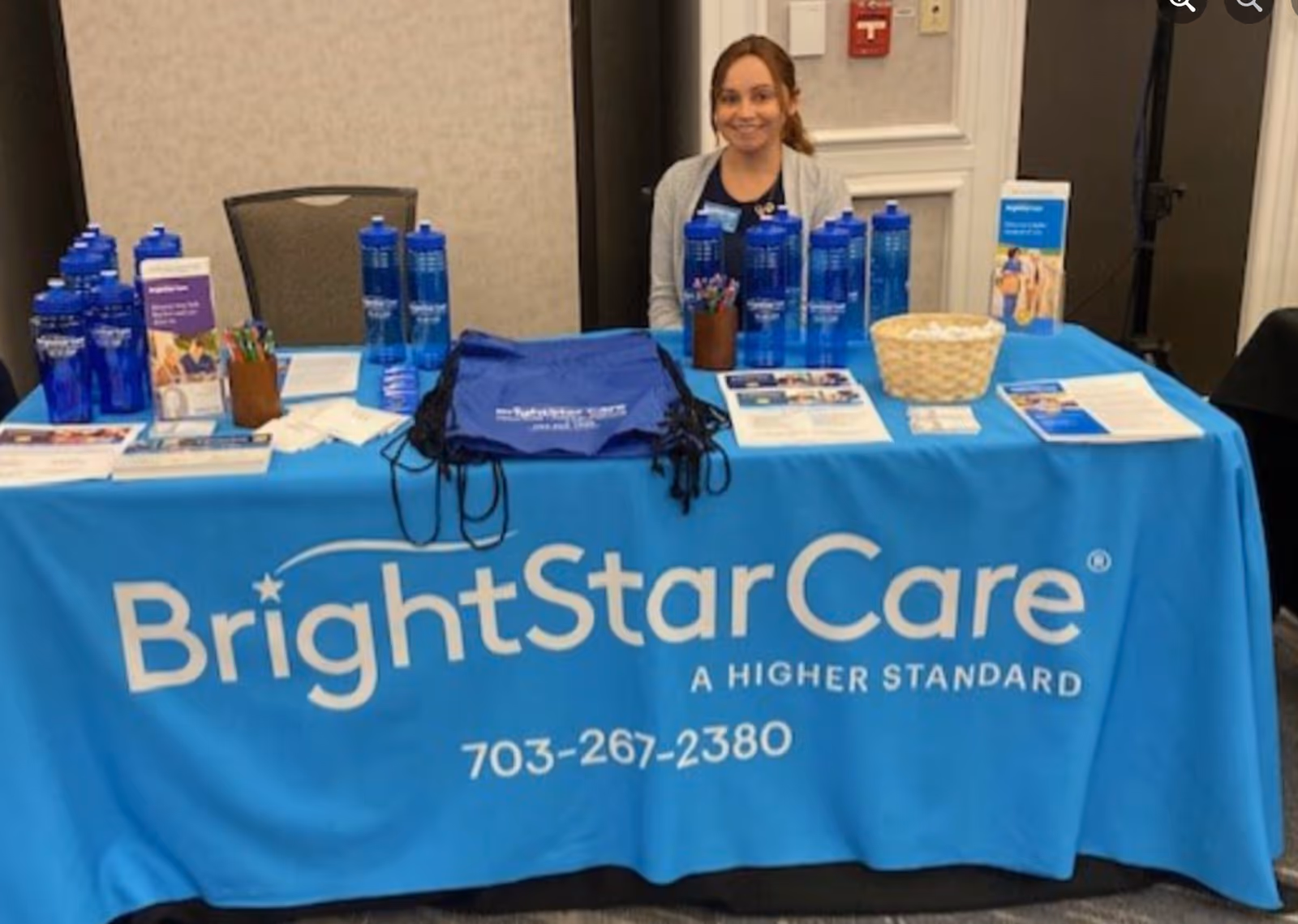 Indoor BrightStarCare promotional booth with a smiling staff member and branded materials.
