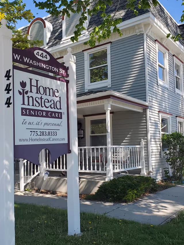 Two-story Home Instead senior care building with a visible front porch sign.