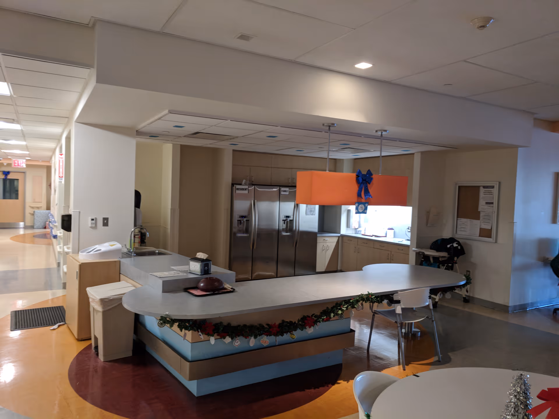 Interior facility kitchen with curved counter, stainless steel appliances, and holiday decorations.