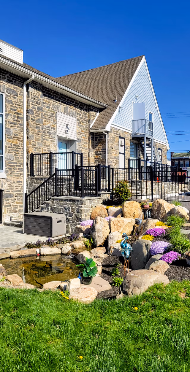 Stone exterior of a senior living facility with landscaped rocks and a small pond.