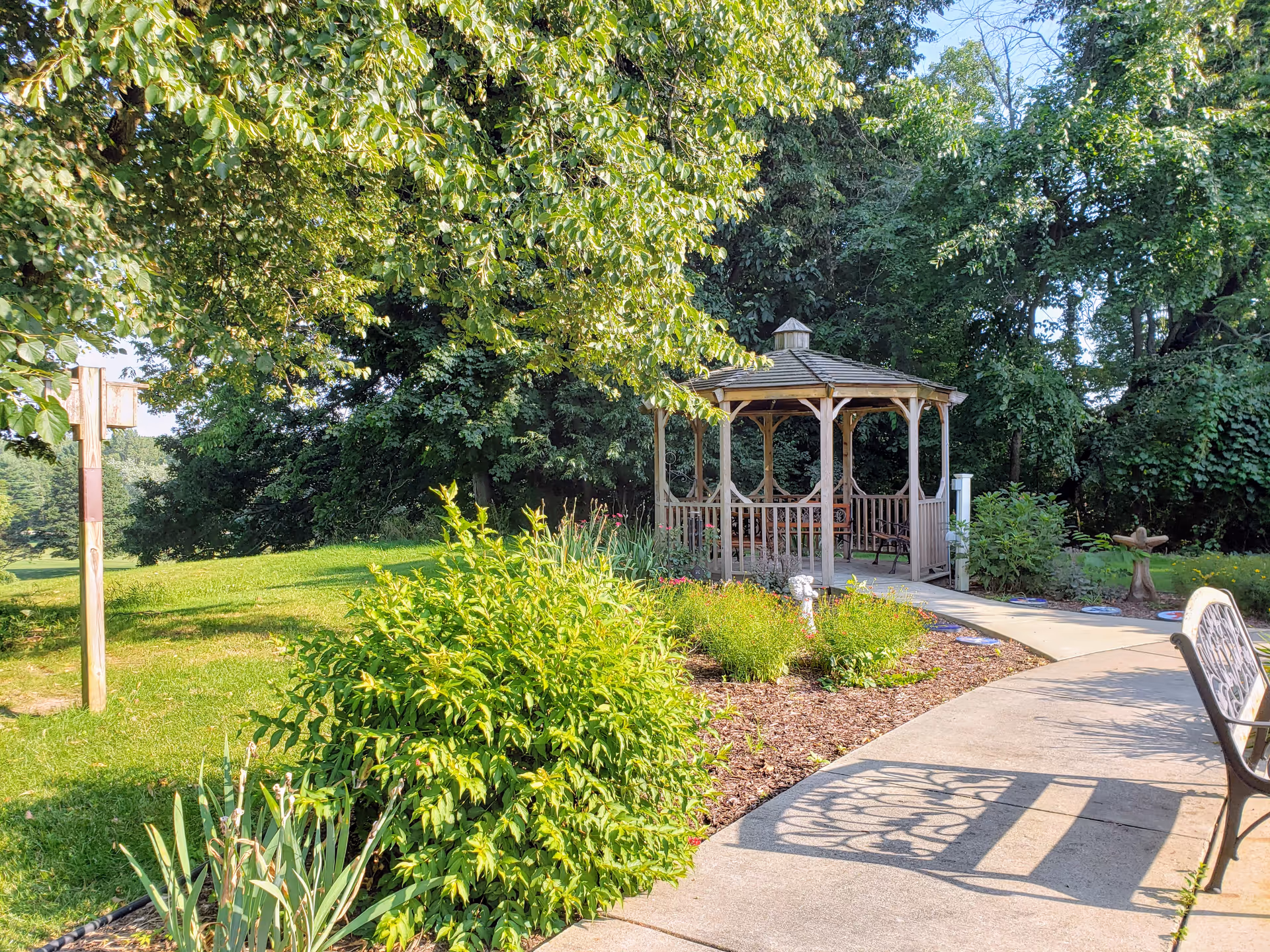A tranquil garden with a wooden gazebo, winding walkway, and greenery.