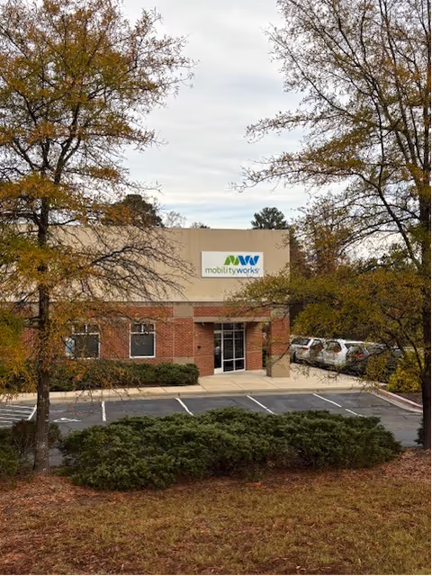 Exterior view of MobilityWorks building with sign, parking lot, and surrounding trees.