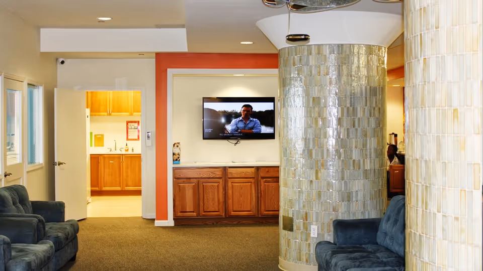 Lobby area with a mounted TV, curved mosaic columns, and seating.