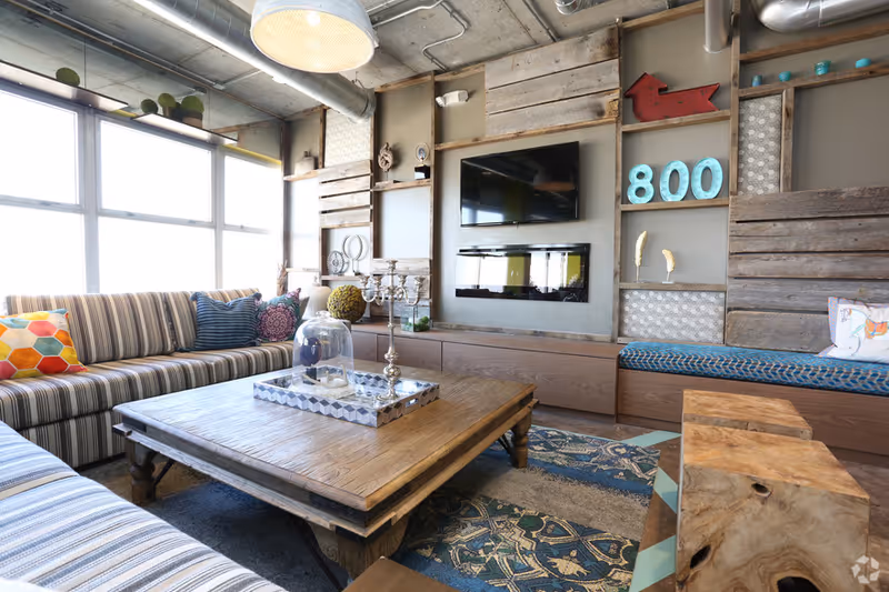 Cozy living room with striped sofa, large windows, wooden coffee table, and wall-mounted TV.