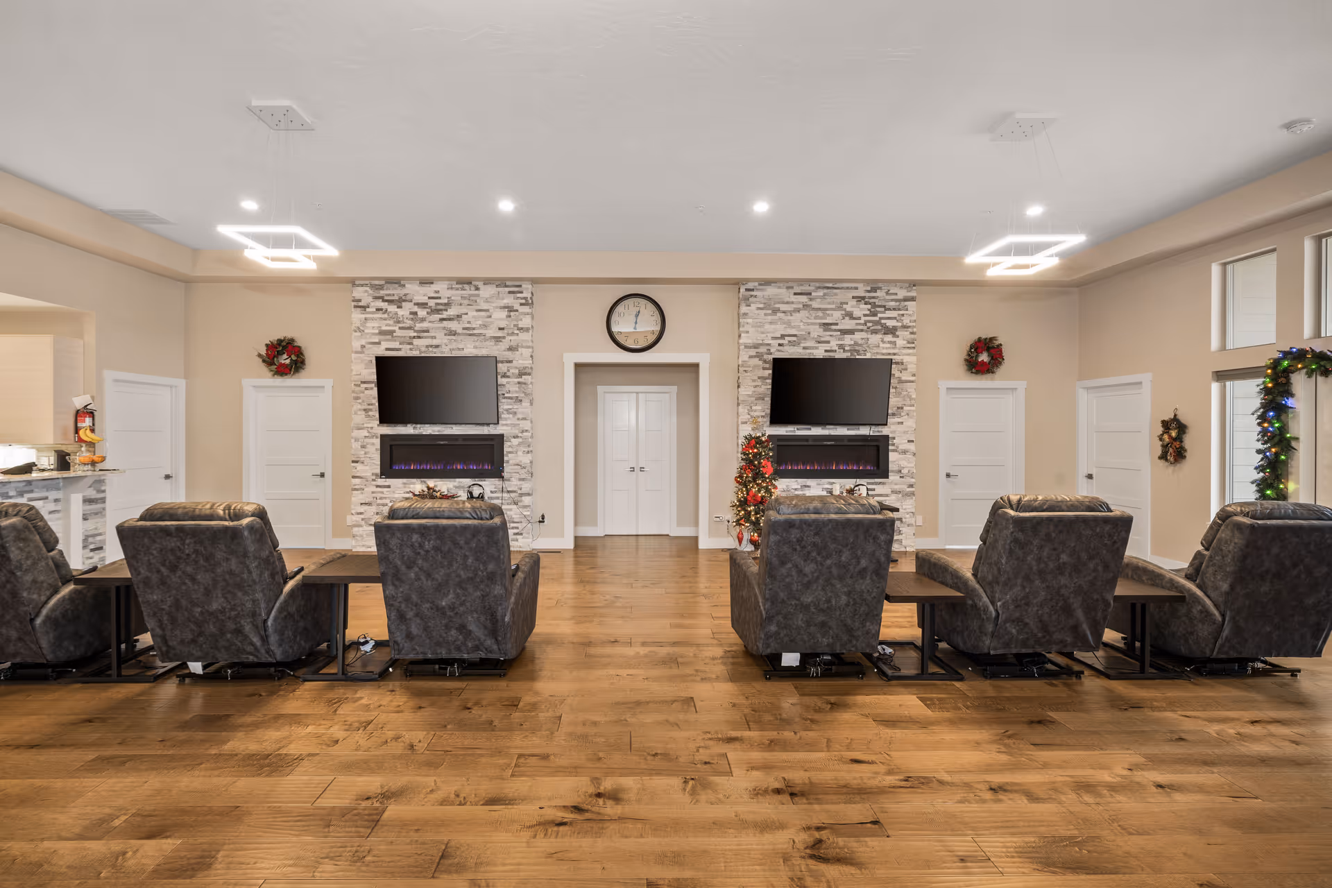 Luxurious senior living lounge with recliners, fireplaces, and wall-mounted TVs.
