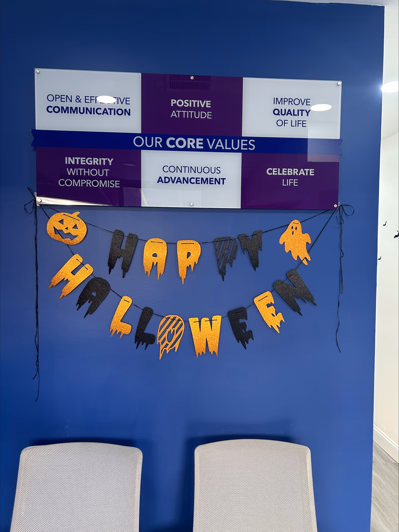 Blue wall with core values sign, Halloween banner, and two chairs in foreground