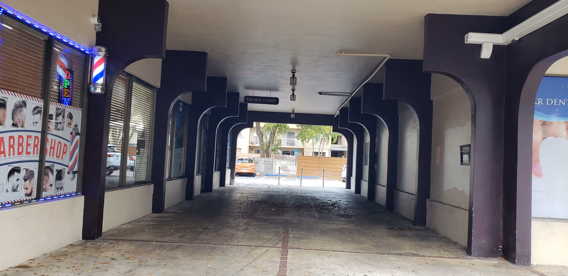 A covered commercial arcade with purple arches and a barber shop on the left.