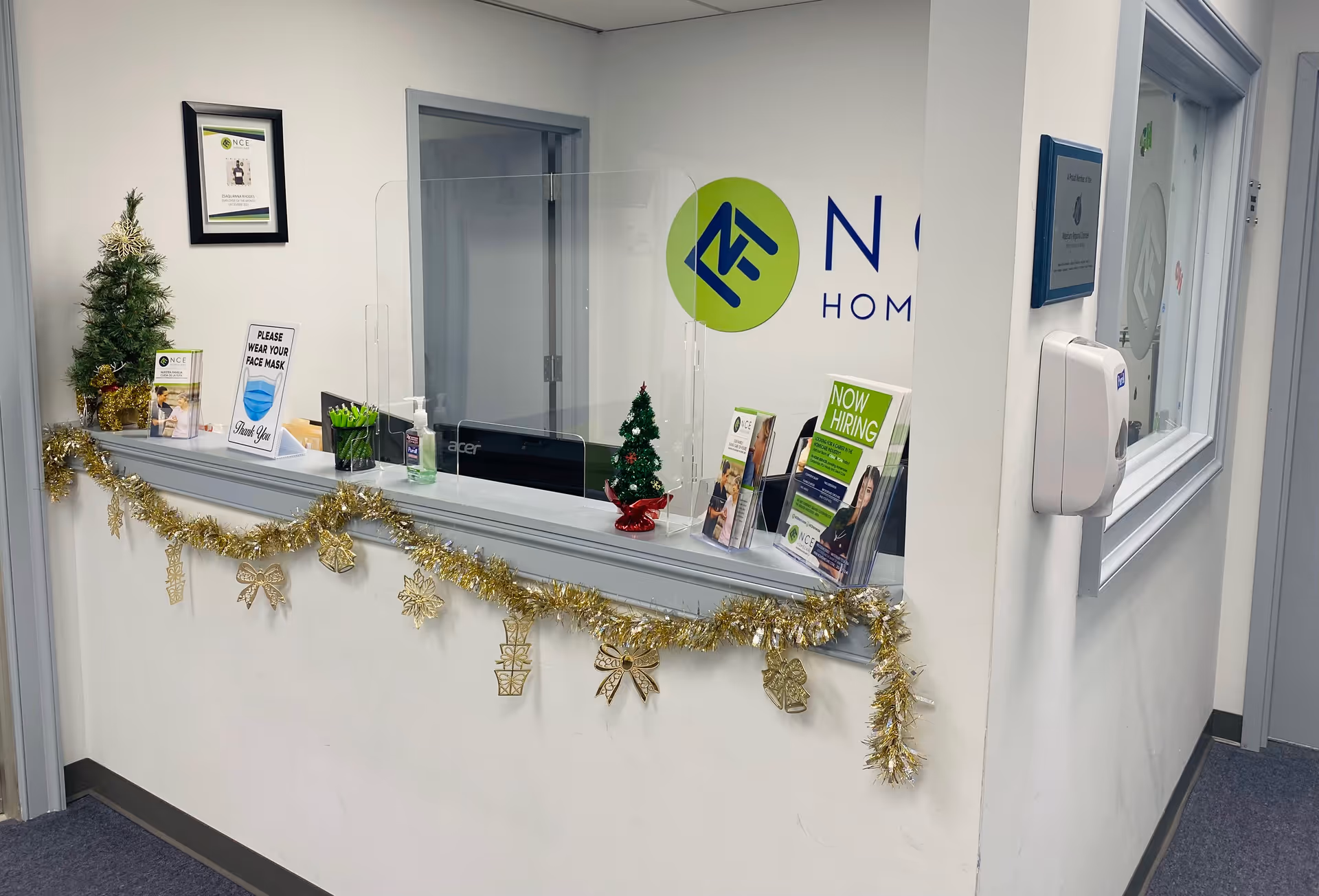 Reception desk inside a facility with NCE Homecare logo, holiday garlands, and brochures.