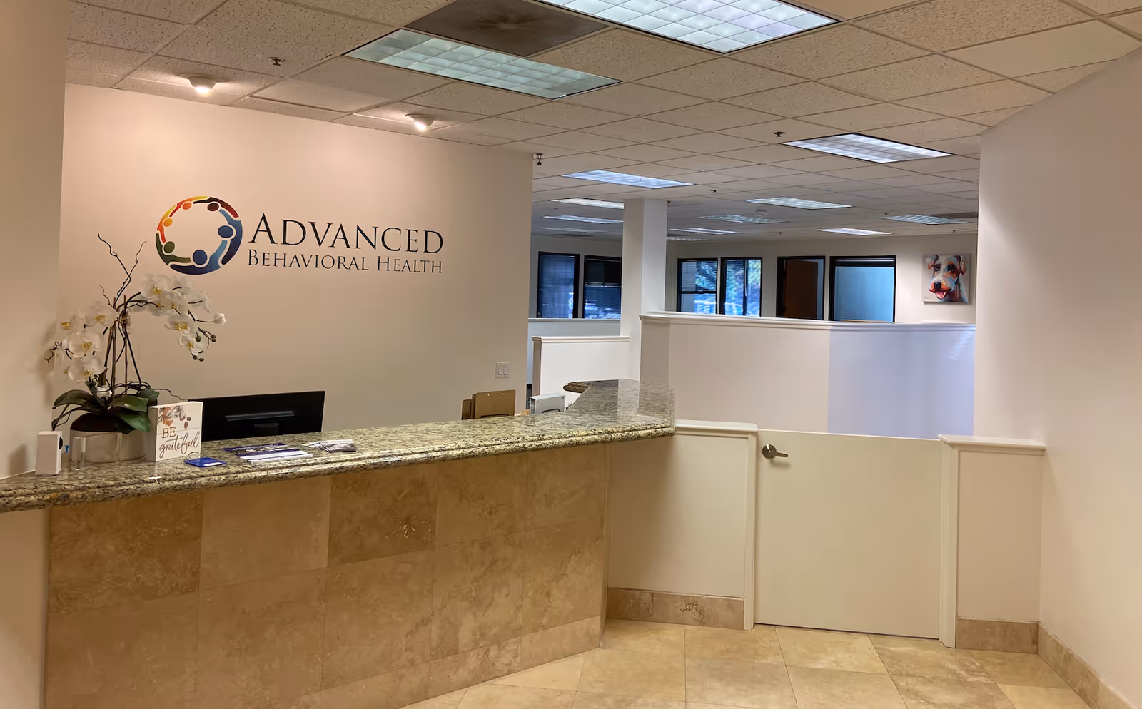 Reception desk in a spacious lobby with the Advanced Behavioral Health logo on the wall.