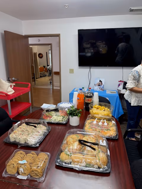 Table loaded with sandwiches, pastries, and drinks in a senior care dining area.