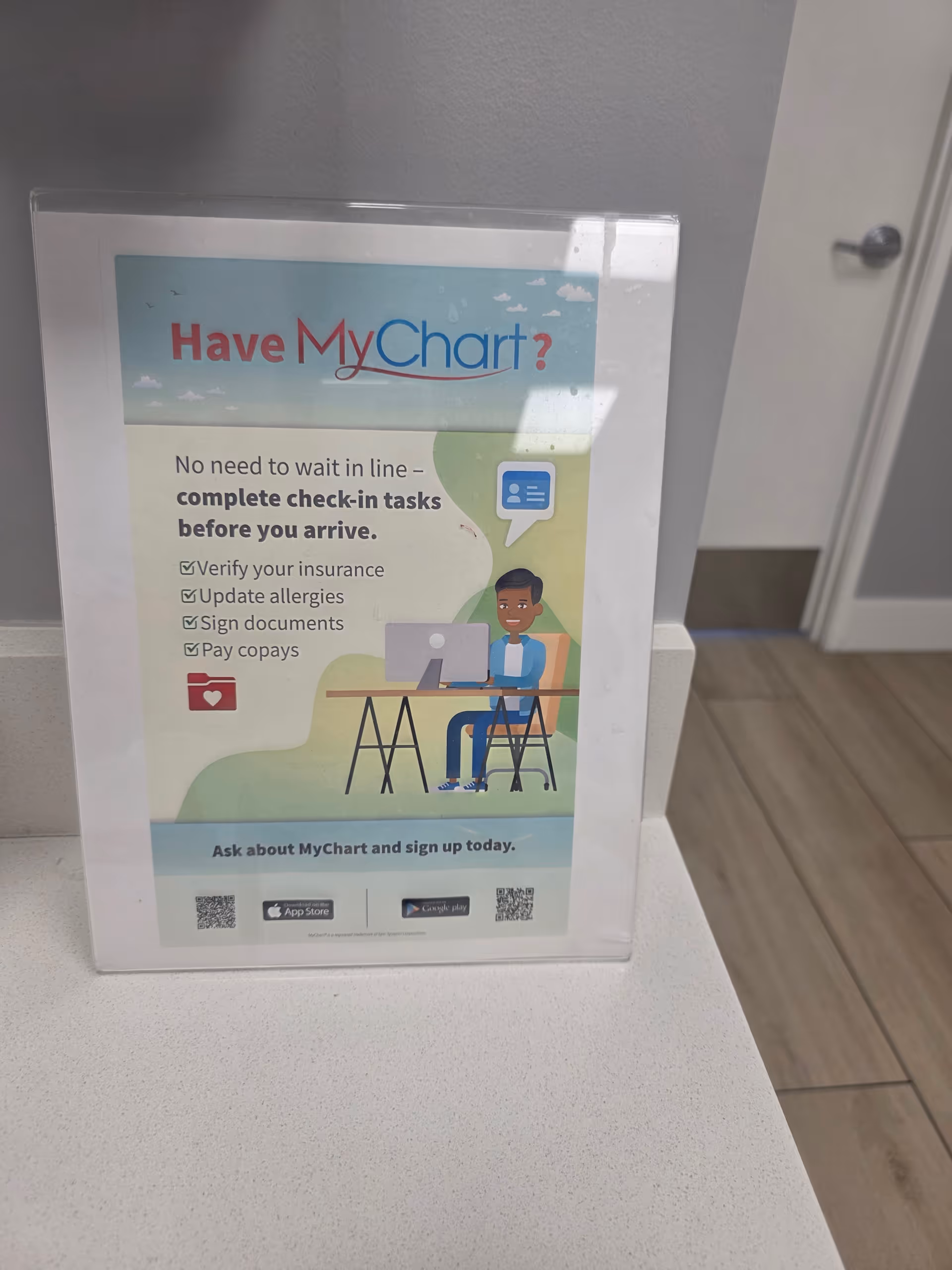Indoor poster promoting MyChart check-in on a counter inside a facility.