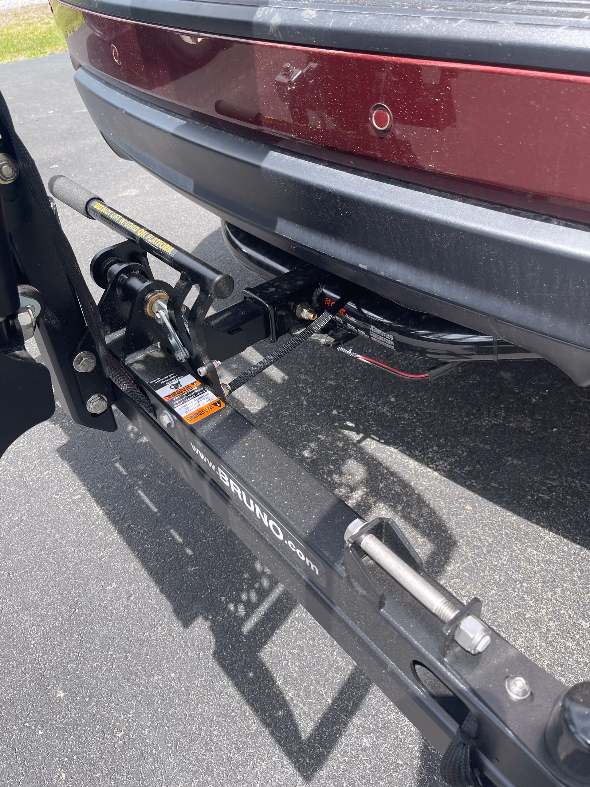 Close-up of a Bruno hitch and mobility lift attached to a vehicle outdoors