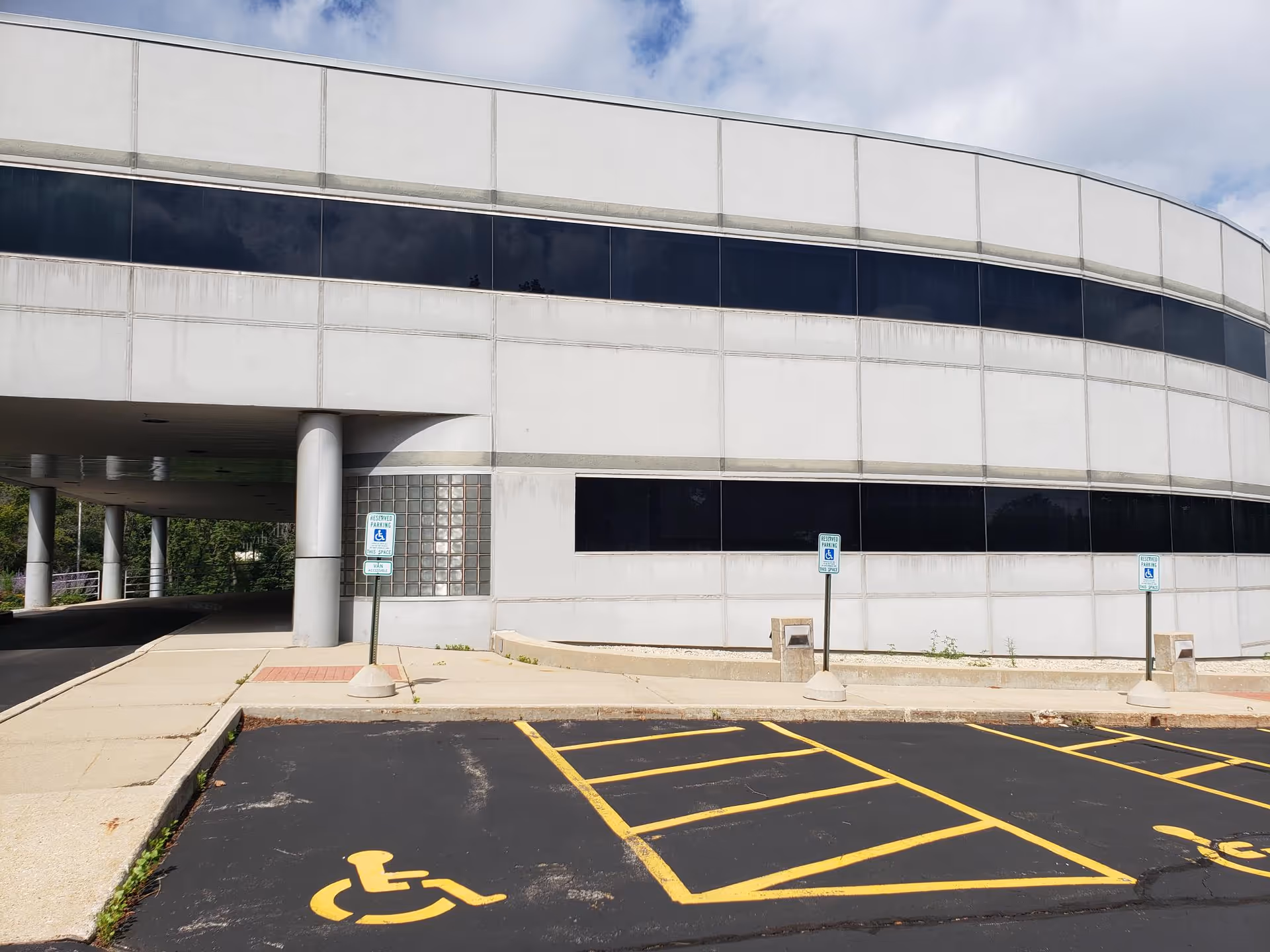 Front view of a curved gray hospice building with handicap parking spaces.