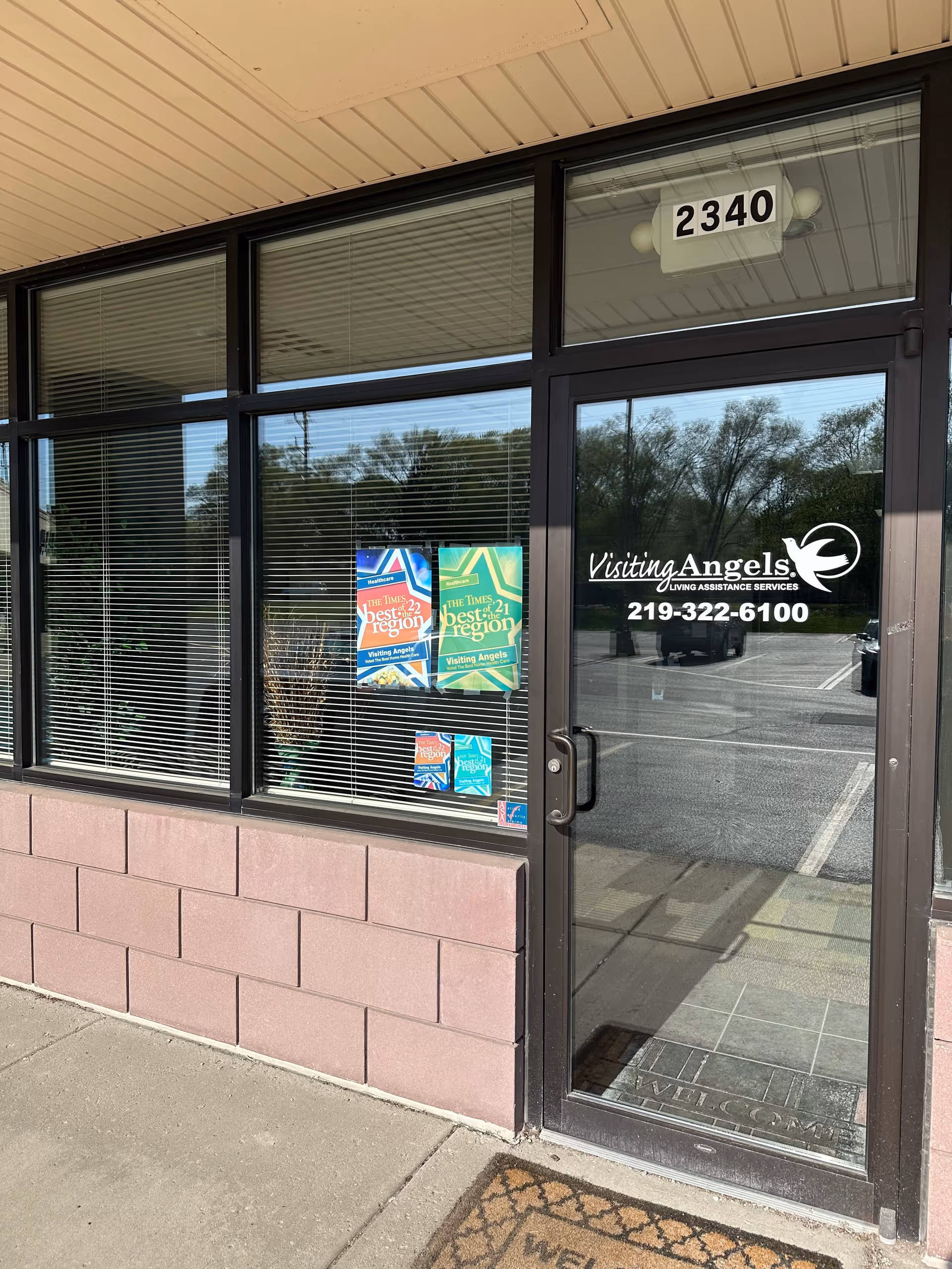 Front entrance of Visiting Angels Senior Home Care building with glass doors, windows, and posters.