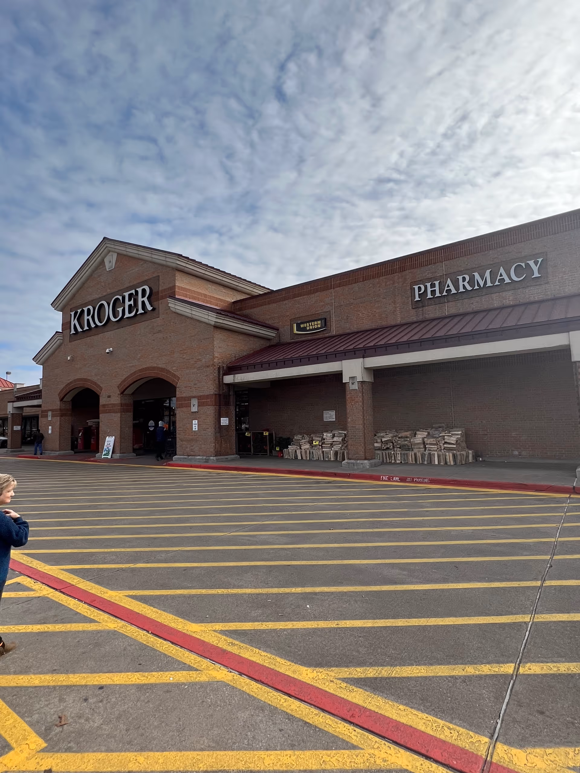 Exterior view of a Kroger Pharmacy storefront with brick facade and marked parking.