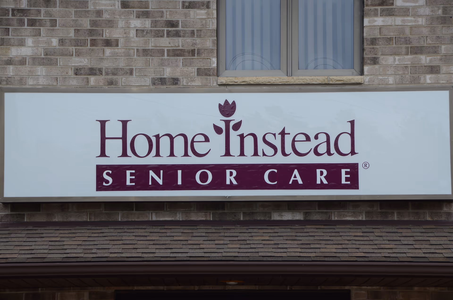 Brick building facade with a large Home Instead Senior Care sign.